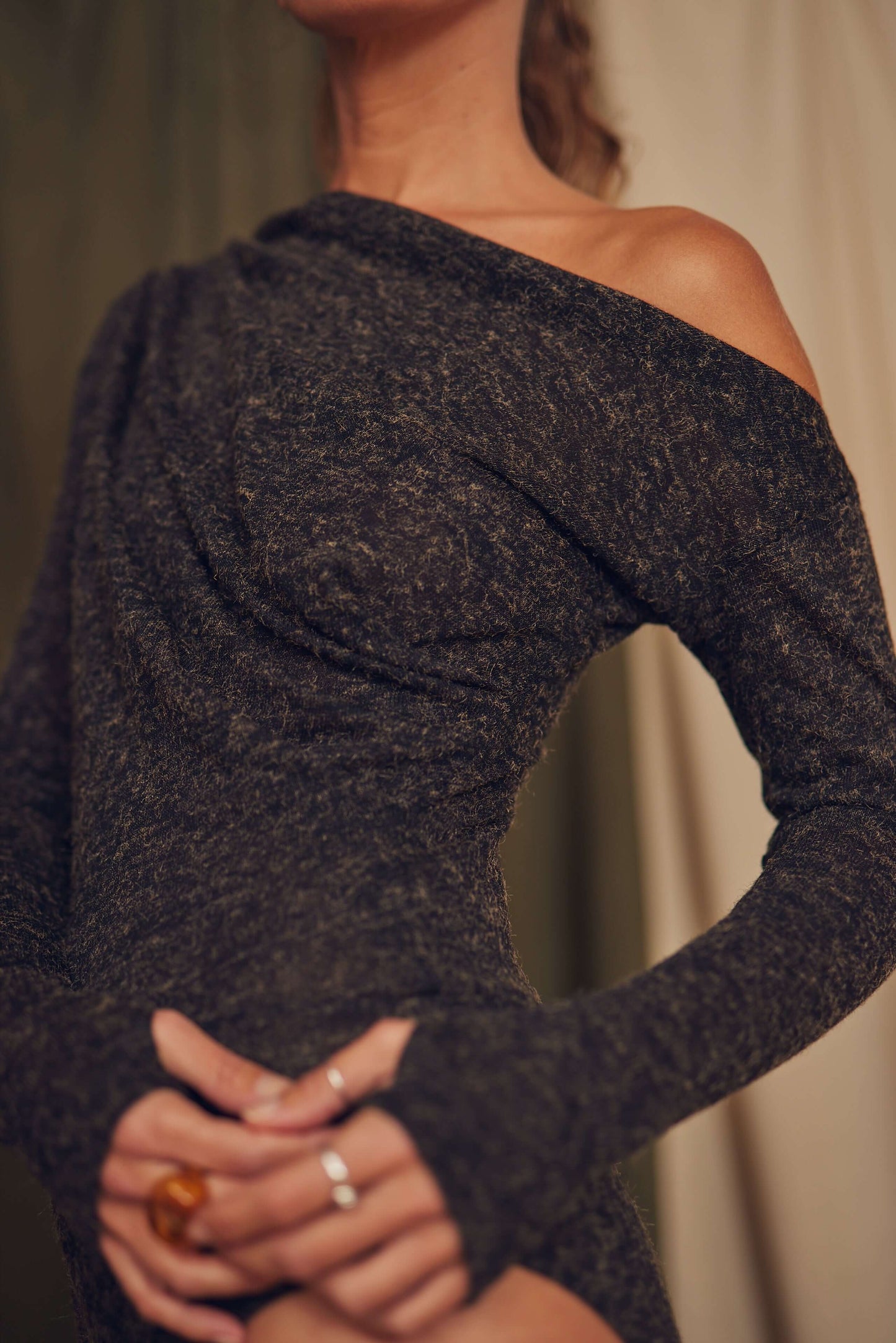 Model wearing a black recycled jersey drape bodysuit with long sleeves and thumb holes, showcasing a chic design.