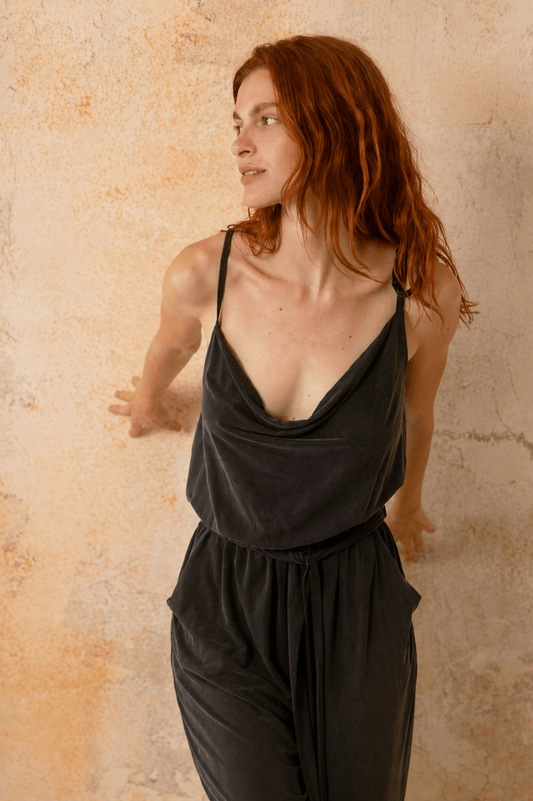 Cupro Slip Jumpsuit with Belt in Slate Black on a model against a textured background.