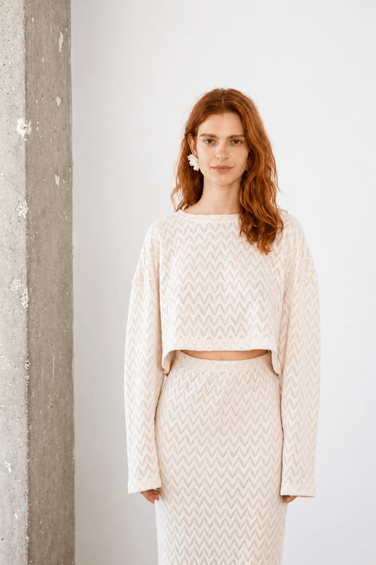 Woman wearing a Crochet Organic Cotton Long Sleeve Top with a matching skirt, showcasing a chic, textured look.