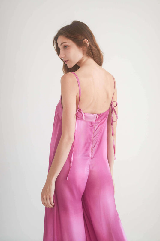 Model wearing a pink printed jumpsuit with self-tie shoulder straps, showcasing a chic back view.