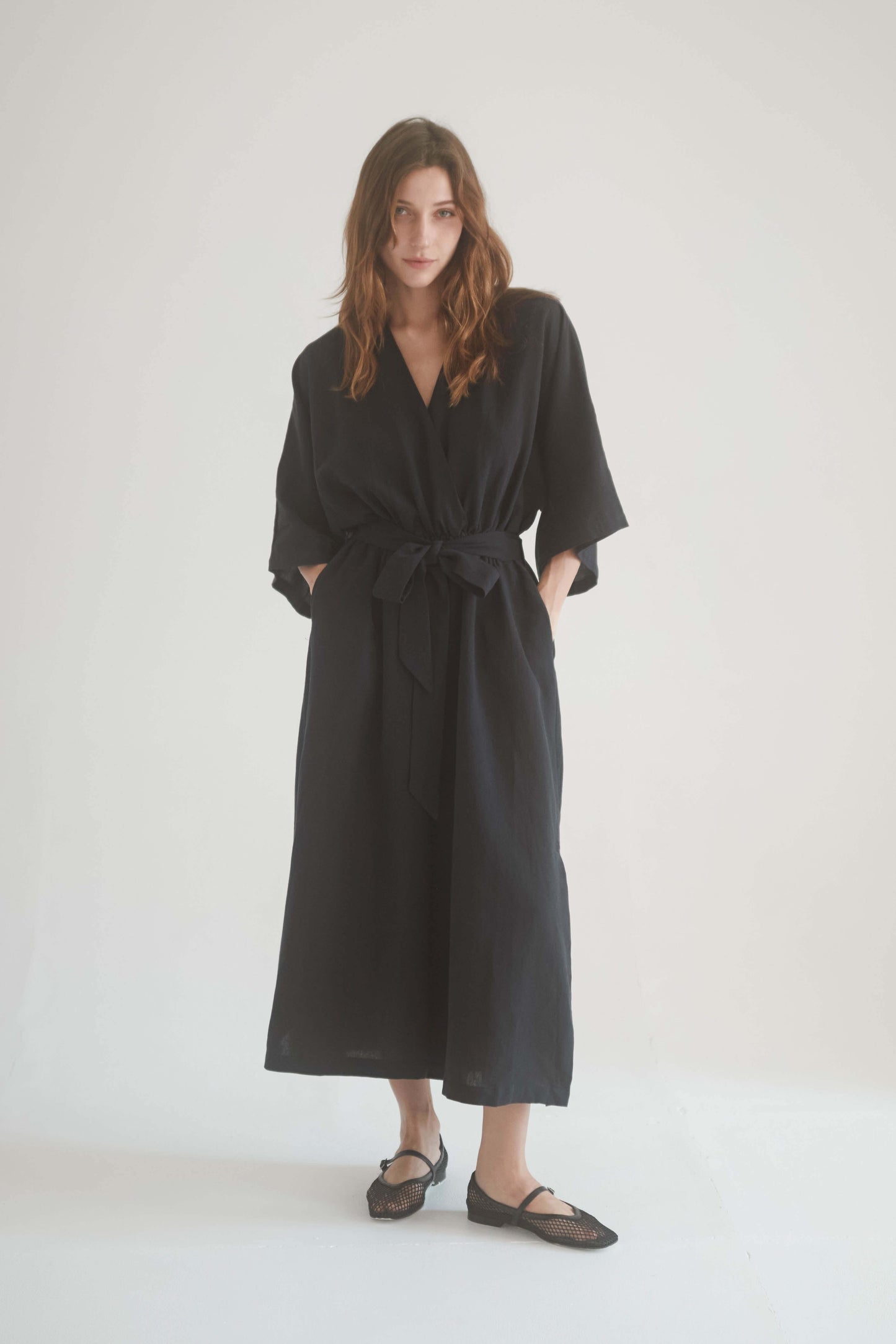 Model wearing a black kimono jumpsuit with a wrap top, side pockets, and elasticated waist, showcasing style and comfort.