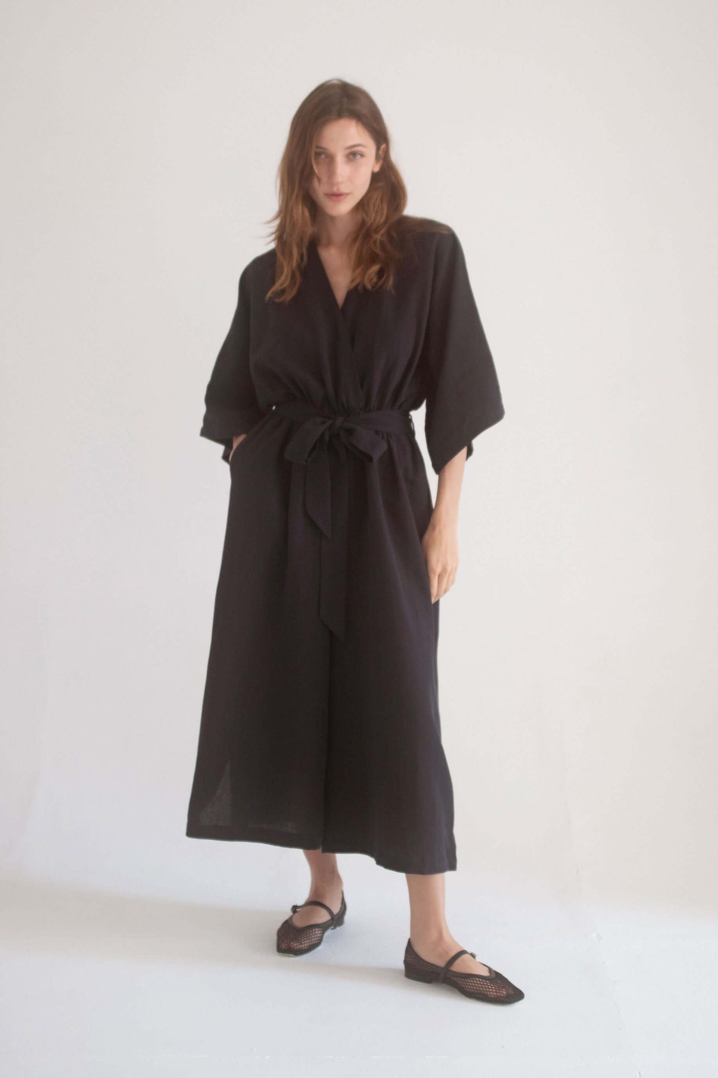 Model wearing a Black Kimono Jumpsuit with wrap top, elastic waist, and side pockets.