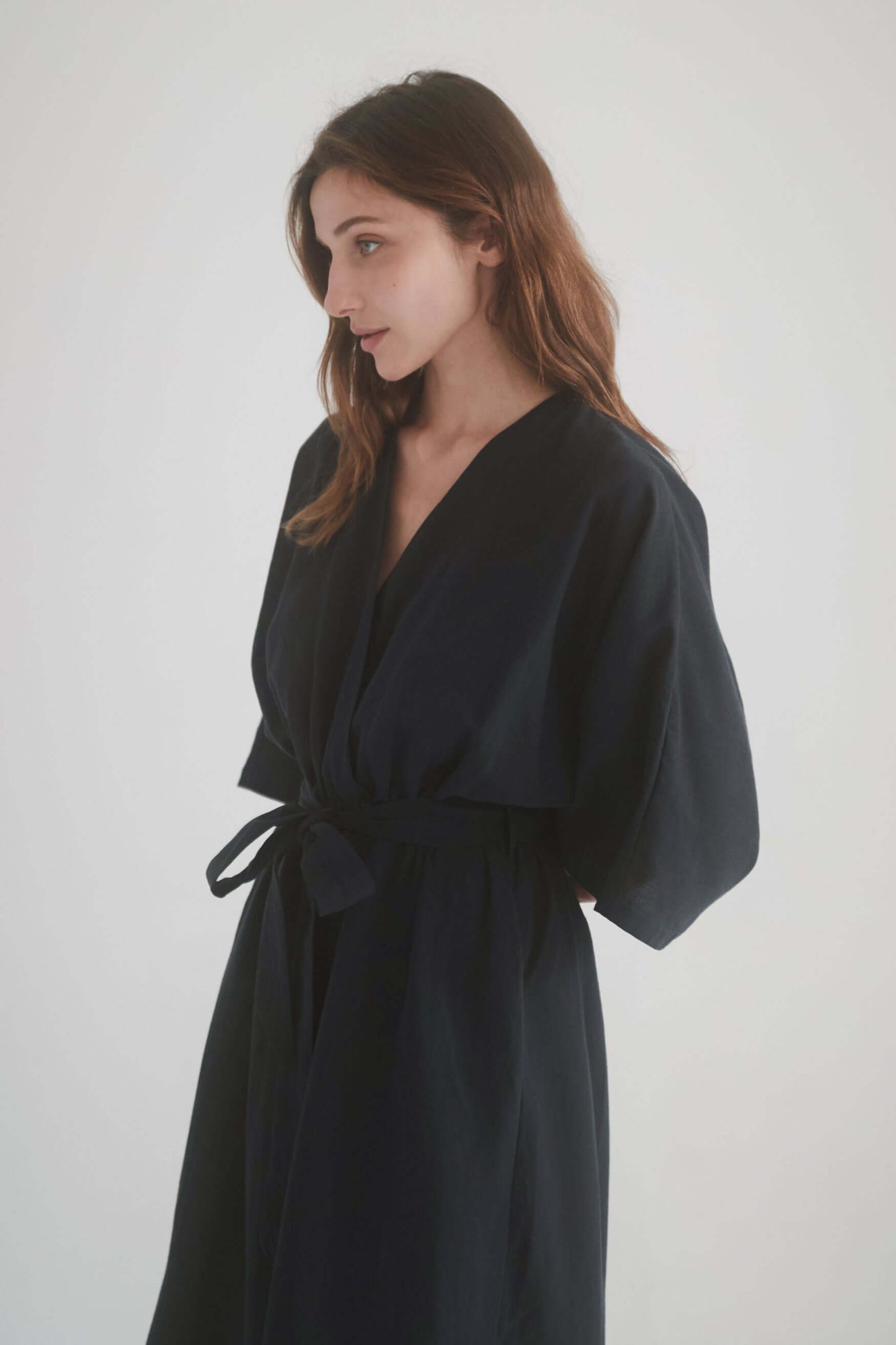 Model wearing a black kimono jumpsuit with a wrap top and tied waist, showcasing a modern and stylish design.