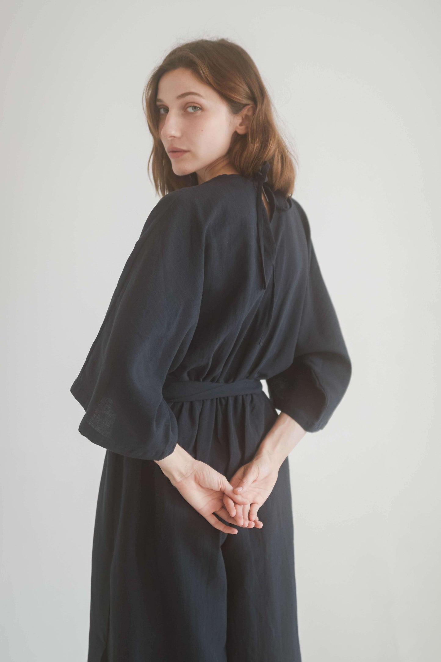 Model wearing a black kimono jumpsuit showcasing the back design and waist tie detail.