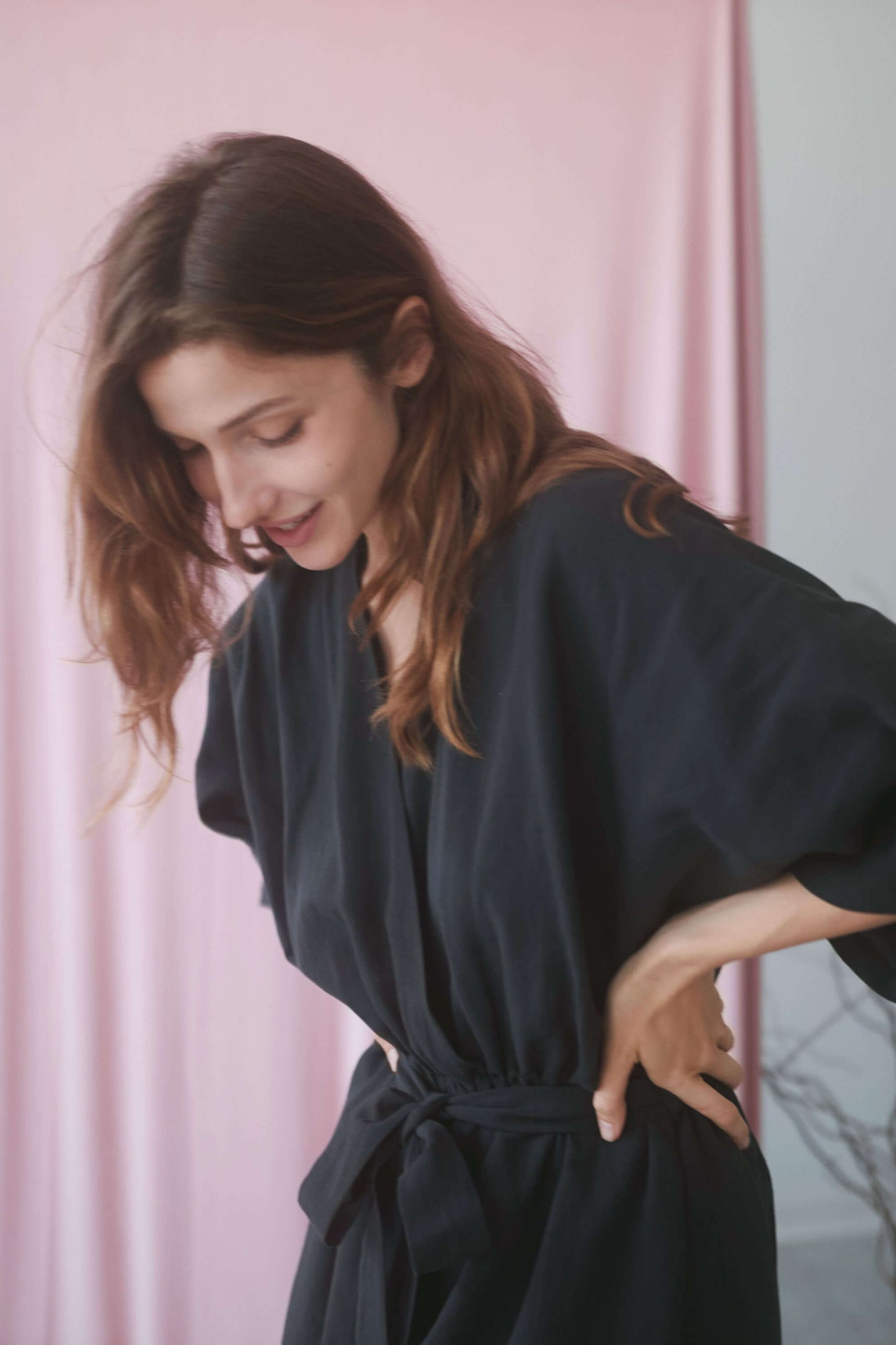 Woman in a black kimono jumpsuit with a belted waist, showcasing a stylish and casual look.