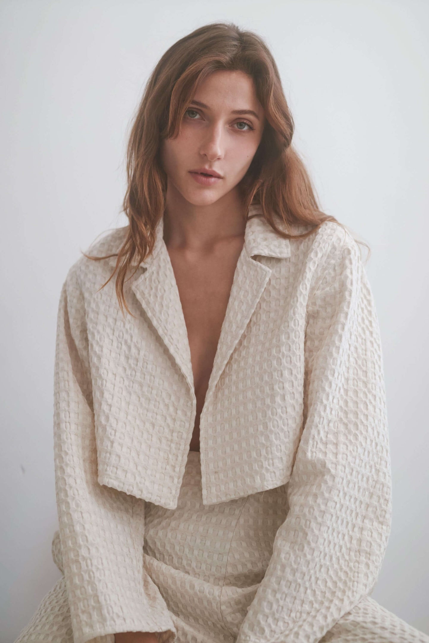 Model wearing a cropped ecru waffle fabric jacket, showcasing its stylish design and premium texture.