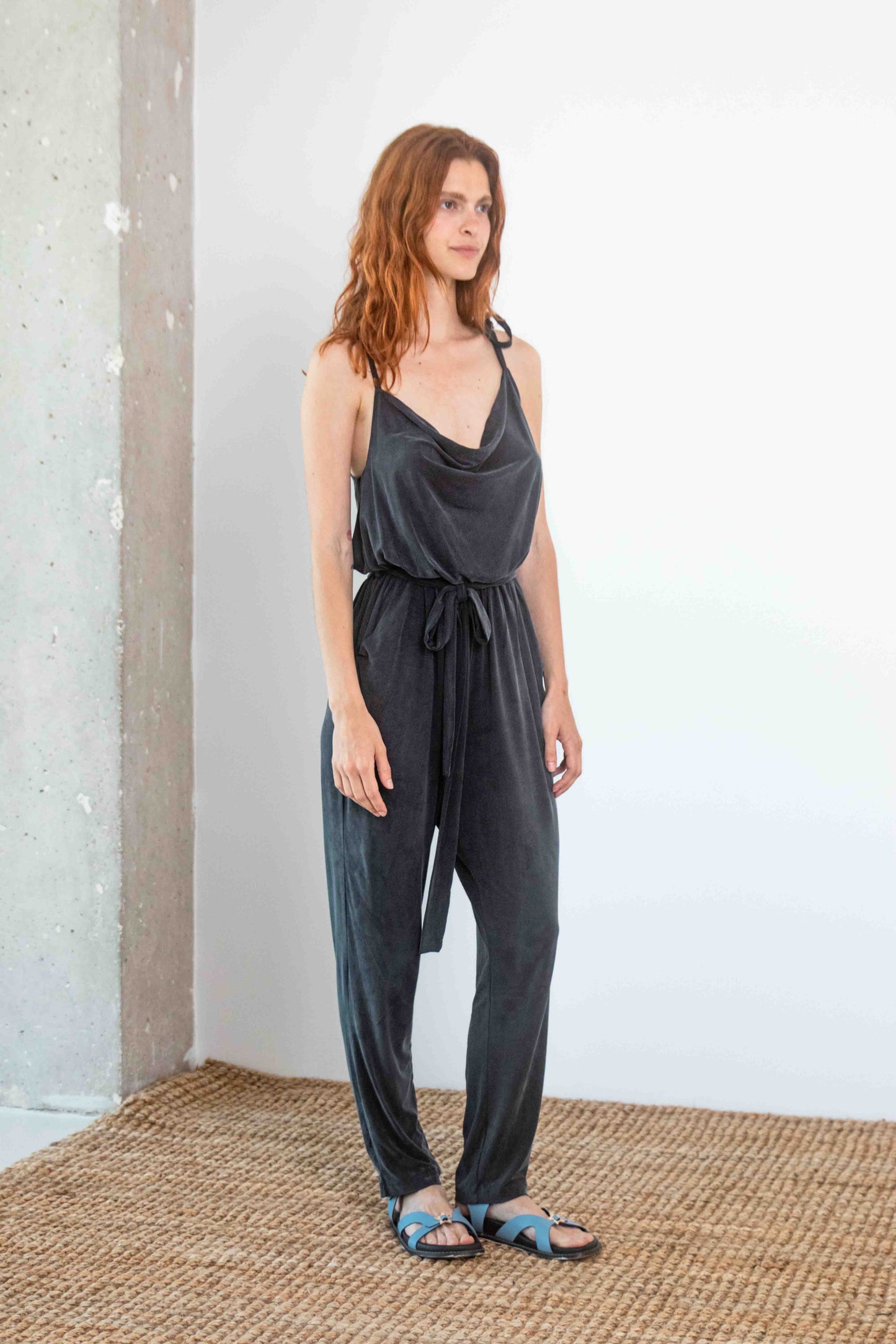 Model wearing Cupro Slip Jumpsuit with Belt in Slate Black, showcasing its relaxed elegance and modern design.