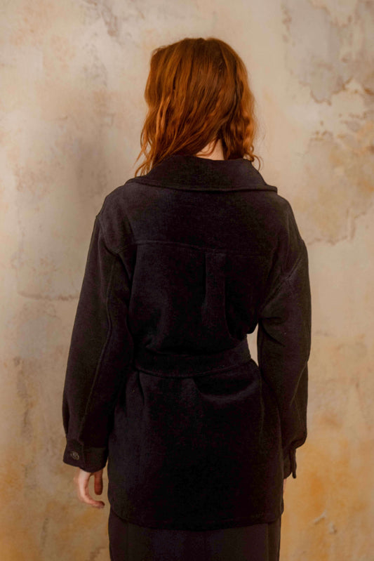 Black Organic Cotton Shacket - ARCHIVE SALE worn by model from the back against a textured wall.