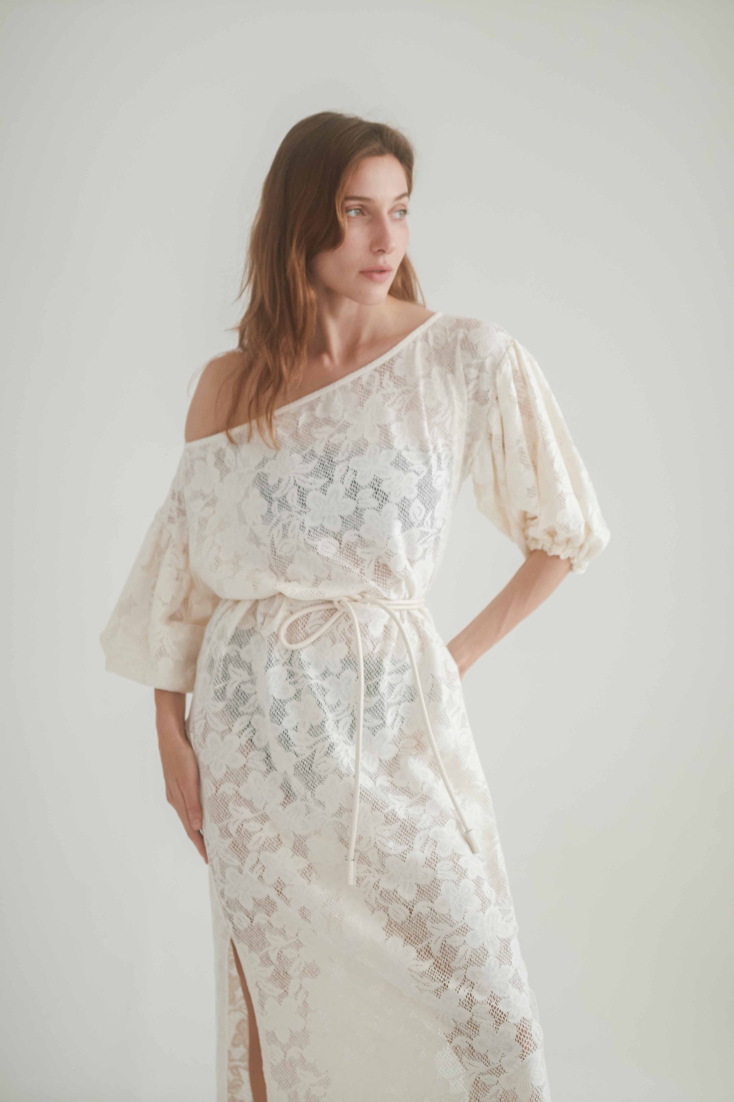 Woman wearing a Lace Boho Maxi Dress with balloon sleeves, featuring a separate lace belt and a side slit.