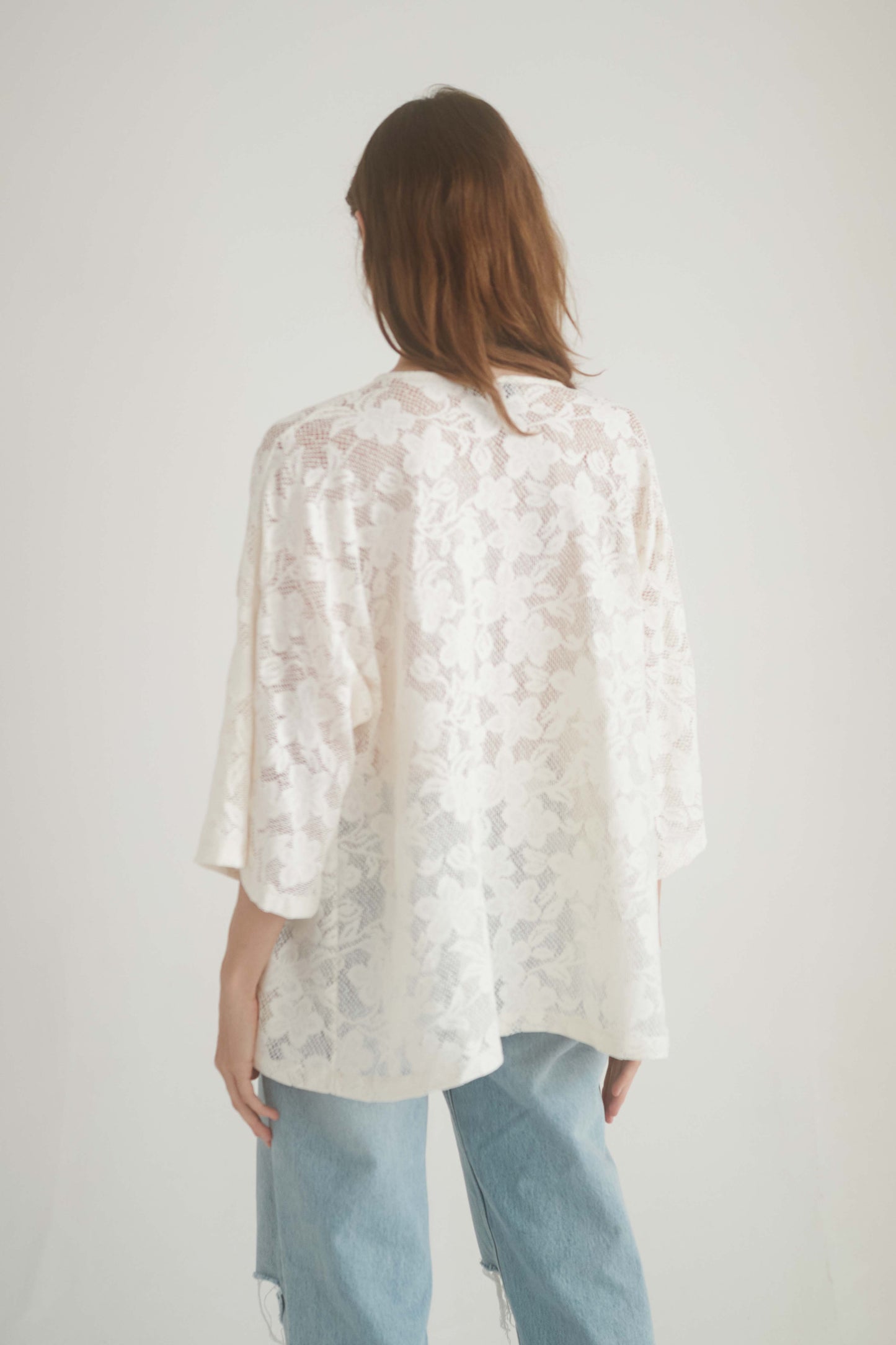 Back view of a woman wearing a lace boho tunic top in ecru, showcasing wide short sleeves and a relaxed silhouette.