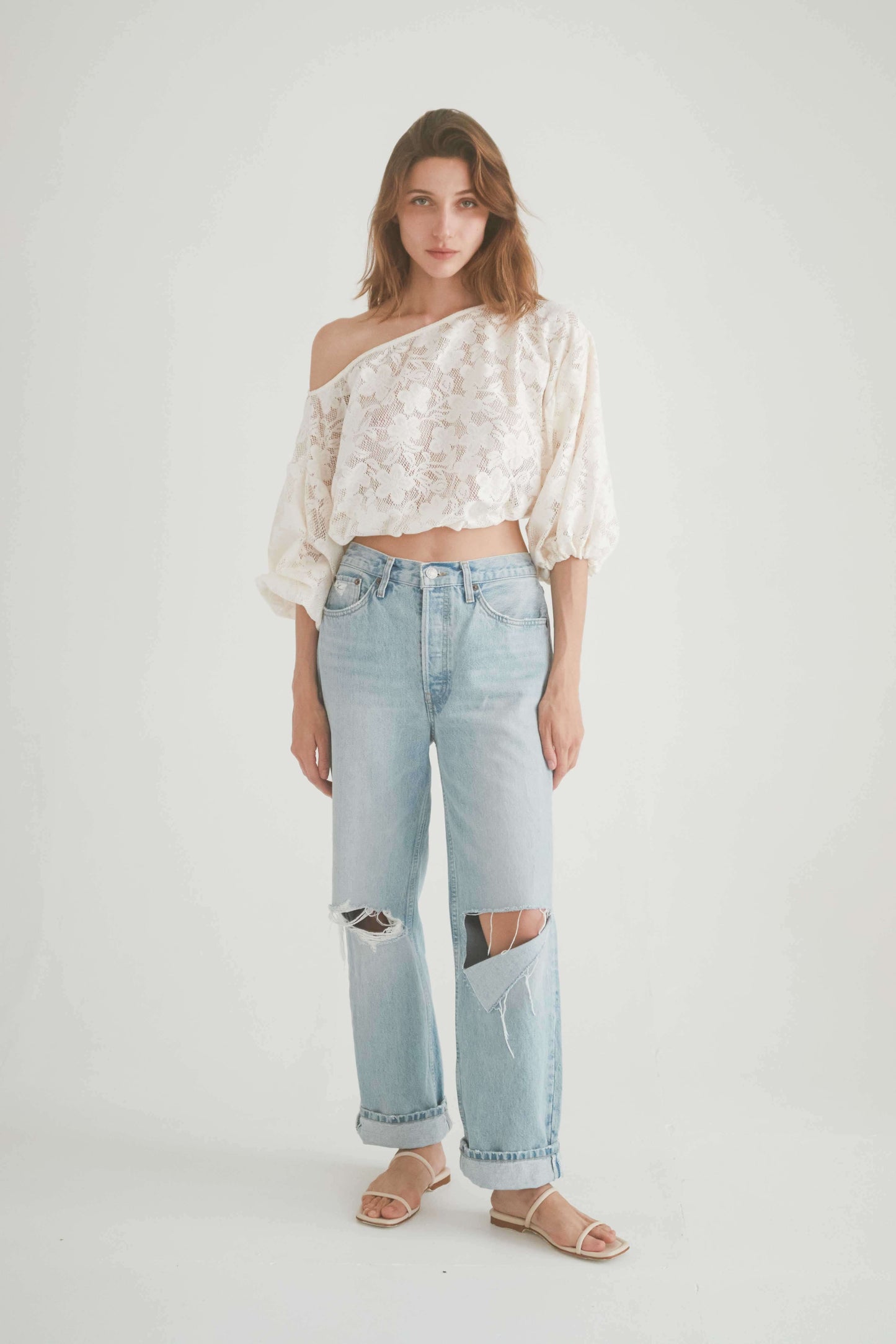 Model wearing LACE BOHO BLOUSE, knitted lace off-shoulder top paired with ripped jeans, exuding bohemian style.