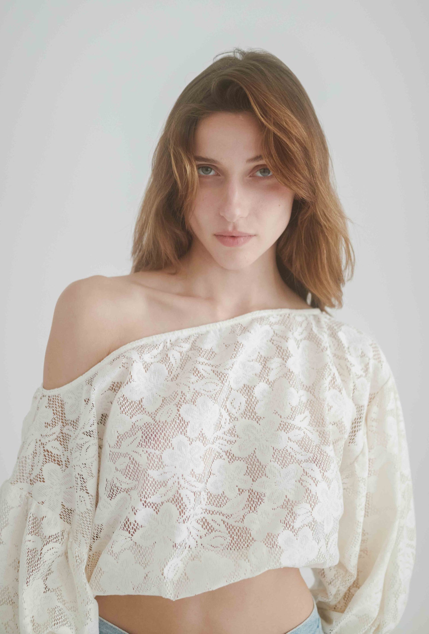 Elegant off-shoulder lace blouse in ecru color, featuring balloon sleeves and a relaxed fit.
