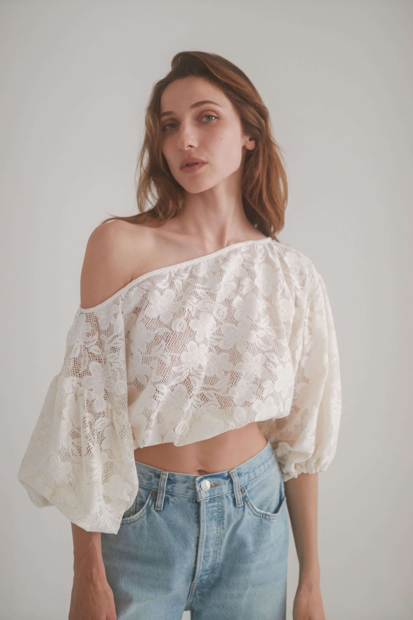 Model wearing a lace boho blouse with off-shoulder neckline and balloon sleeves, styled with jeans.