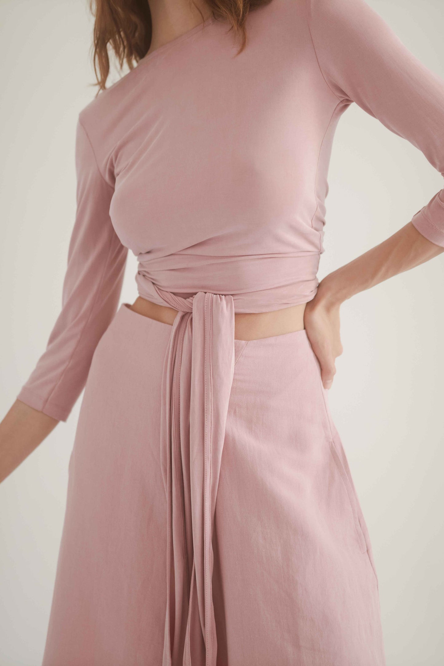 Close-up of a model wearing a pink wrap top styled with rose culottes, showcasing a chic and elegant outfit combination.