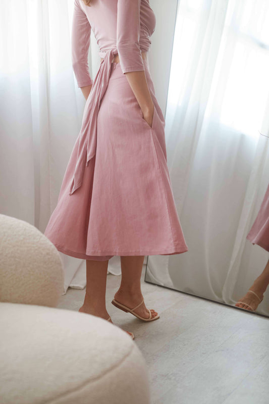 Model wearing rose skirt culottes with pockets and a high waist, styled with a light blouse and sandals.