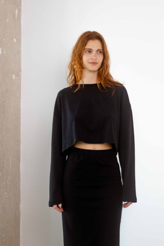Model wearing an Organic Cotton Long Sleeve Top in Black, showcasing a cropped silhouette and relaxed fit.
