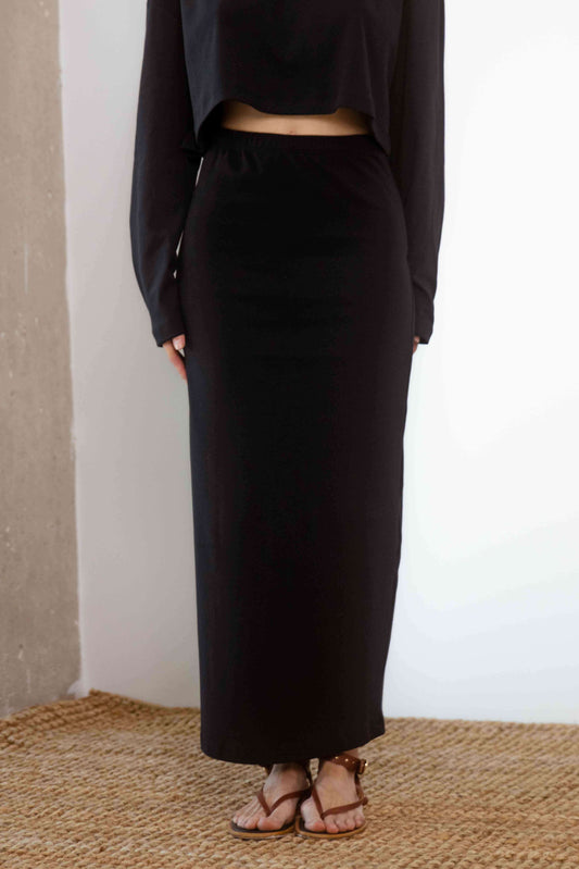 Organic Cotton Midi Skirt in Black worn with a matching top, showcasing its sleek silhouette and comfortable fit.