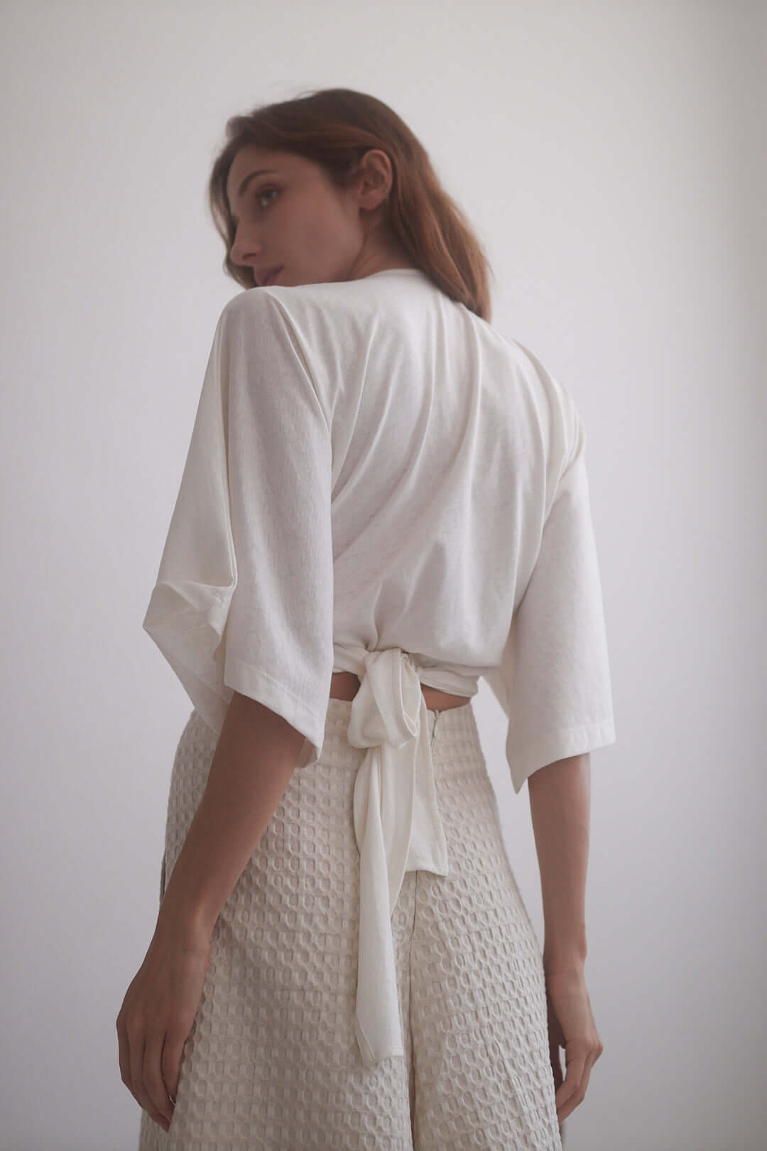 Model wearing ecru kimono wrap top with adjustable ties, showcasing its eco-friendly fabric and oversized fit.