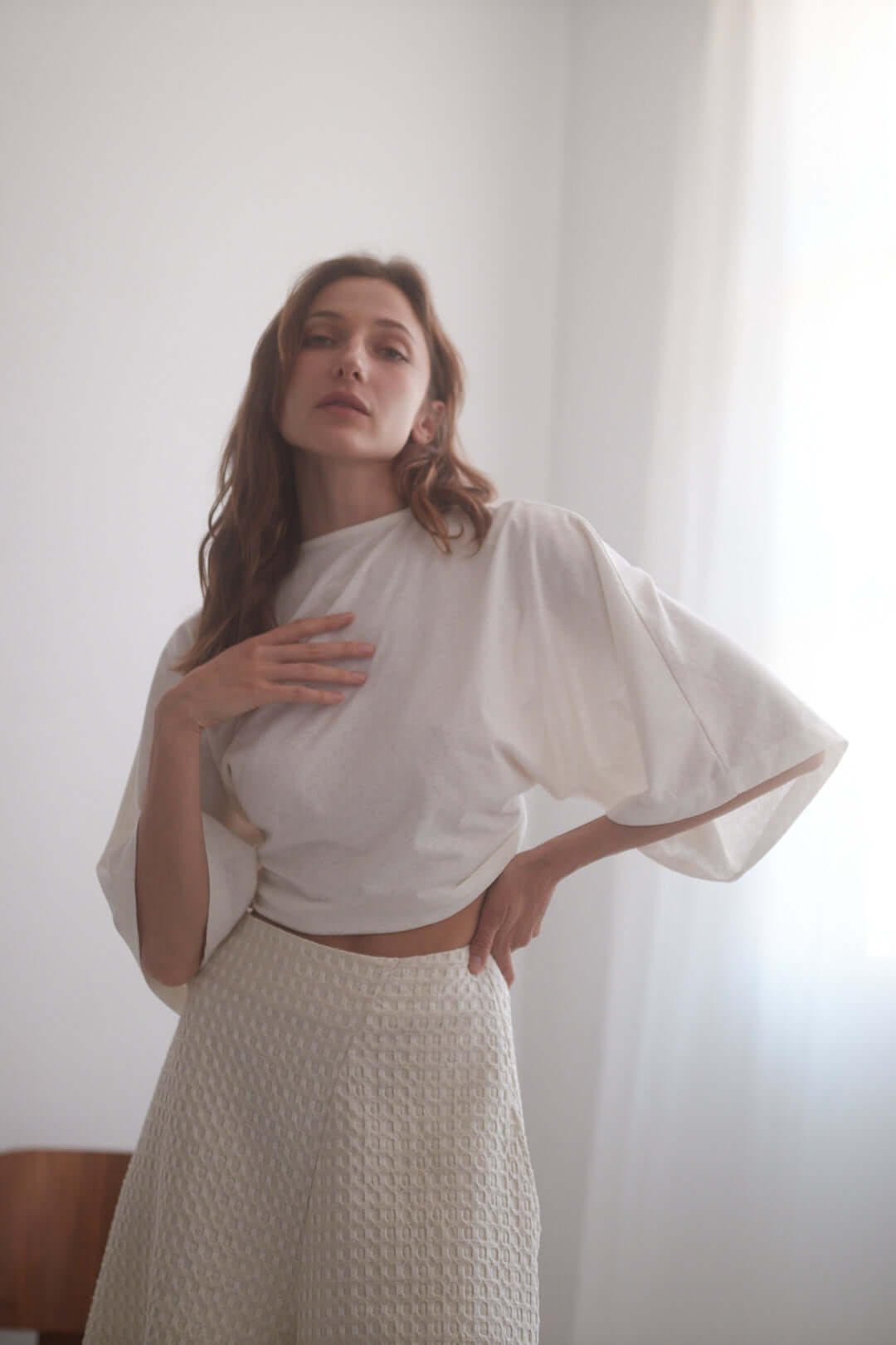 Model wearing an ecru eco-friendly kimono wrap top styled with wide culottes in a bright, airy setting.