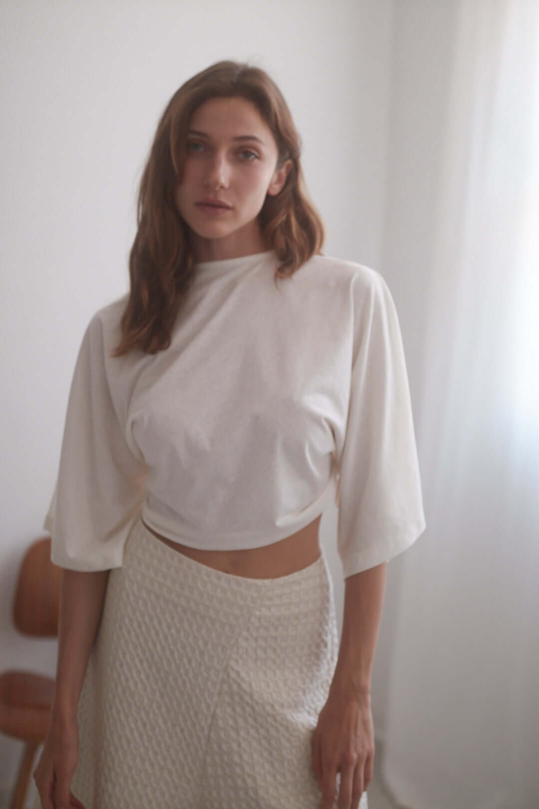 Model wearing an eco-friendly ecru wrap top with oversized sleeves, paired with a light skirt.