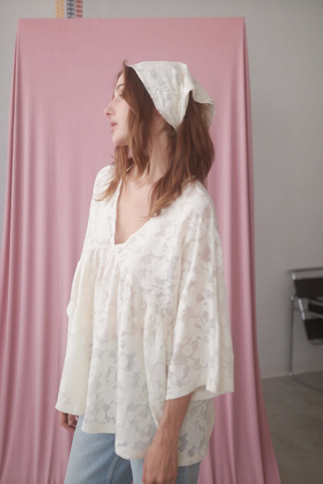Model wearing a small lace scarf and top in soft ecru, showcasing sustainable fashion with organic cotton.