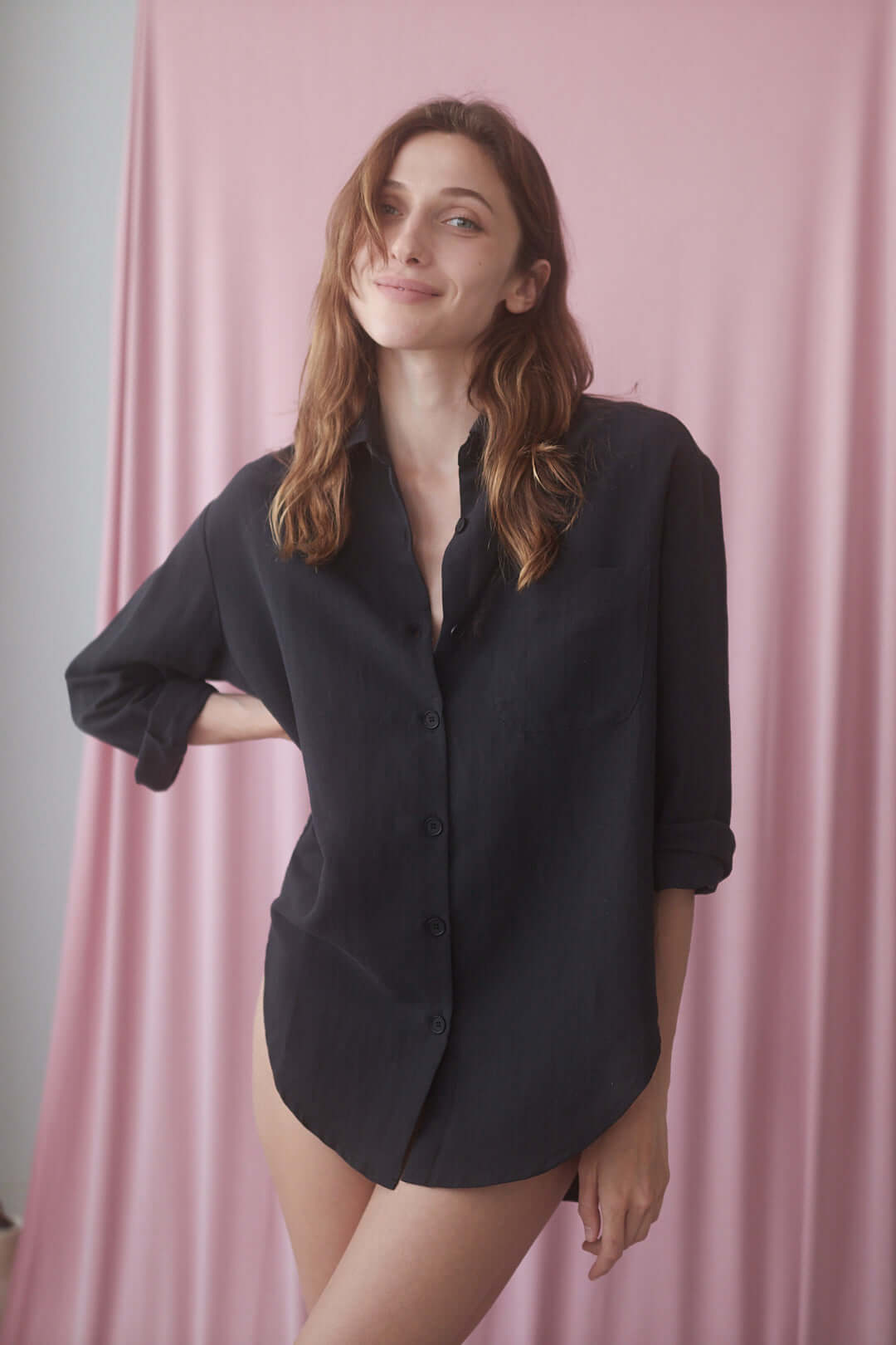 Natural wide shirt in black, featuring eco buttons and an oversized fit, styled against a pastel pink backdrop.