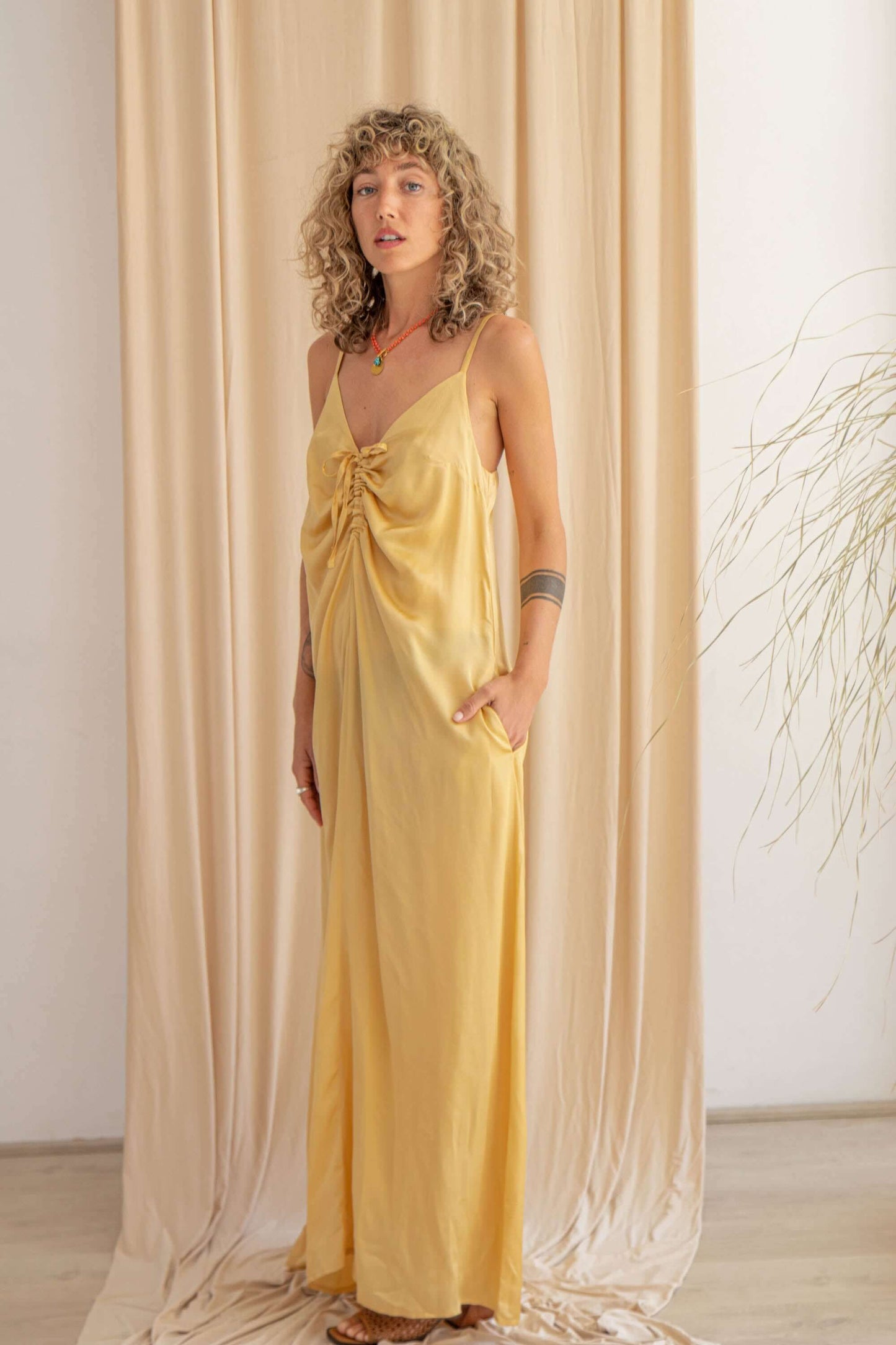 Model wearing a vanilla maxi dress with adjustable straps, showcasing a stylish knot design and pockets.