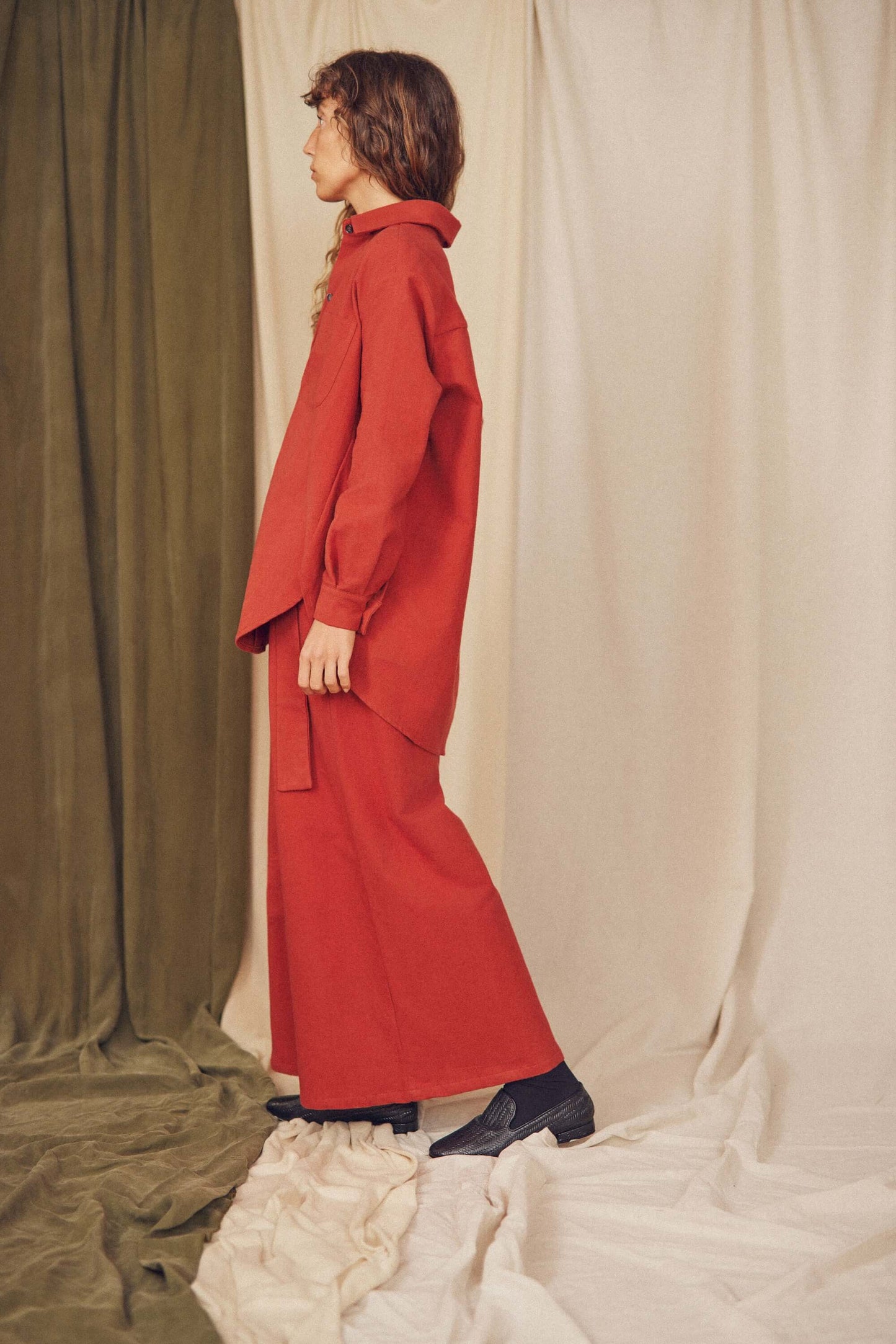Model wearing rust organic cotton wide overshirt with sustainable style, paired with loose-fit trousers, featuring an oversized silhouette.