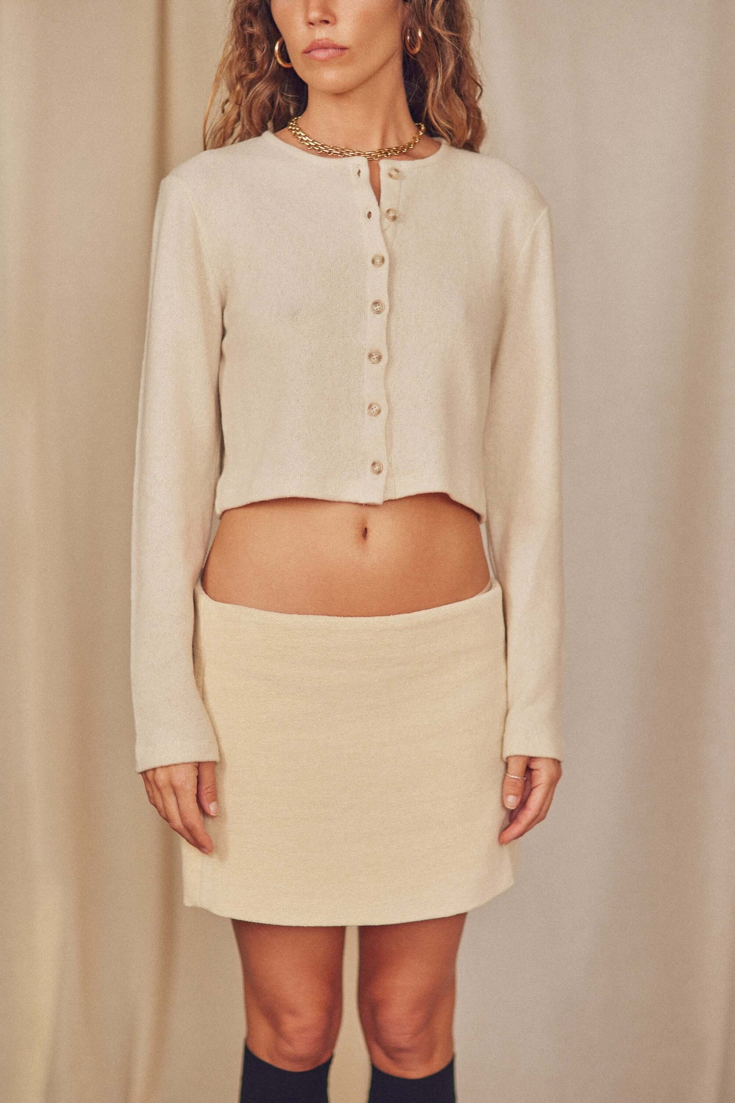 Model wearing an organic cotton cropped top and matching mini skirt, showcasing a chic autumn look.