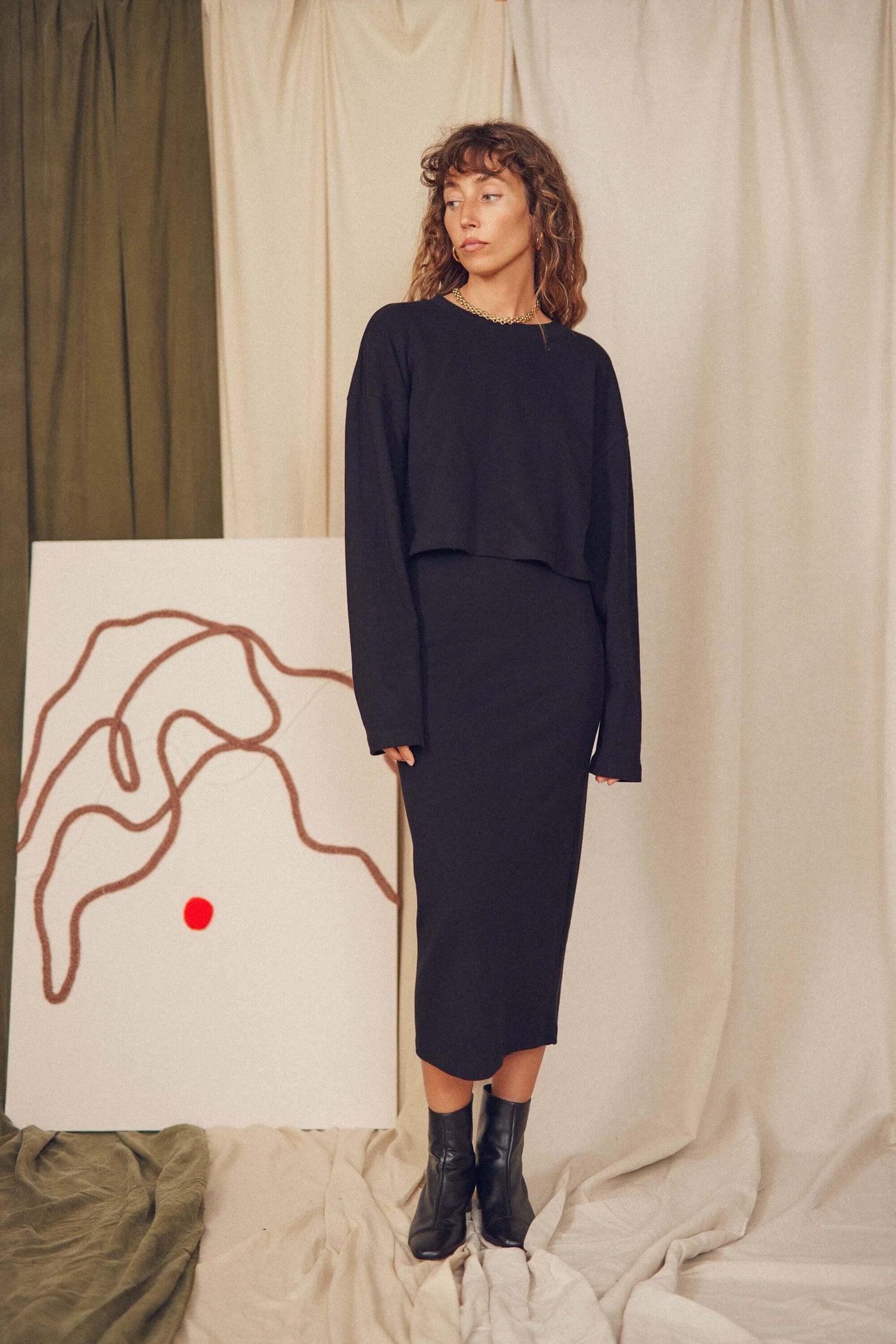 Model wearing a black midi pencil skirt and matching top, showcasing minimalist autumn/winter style.