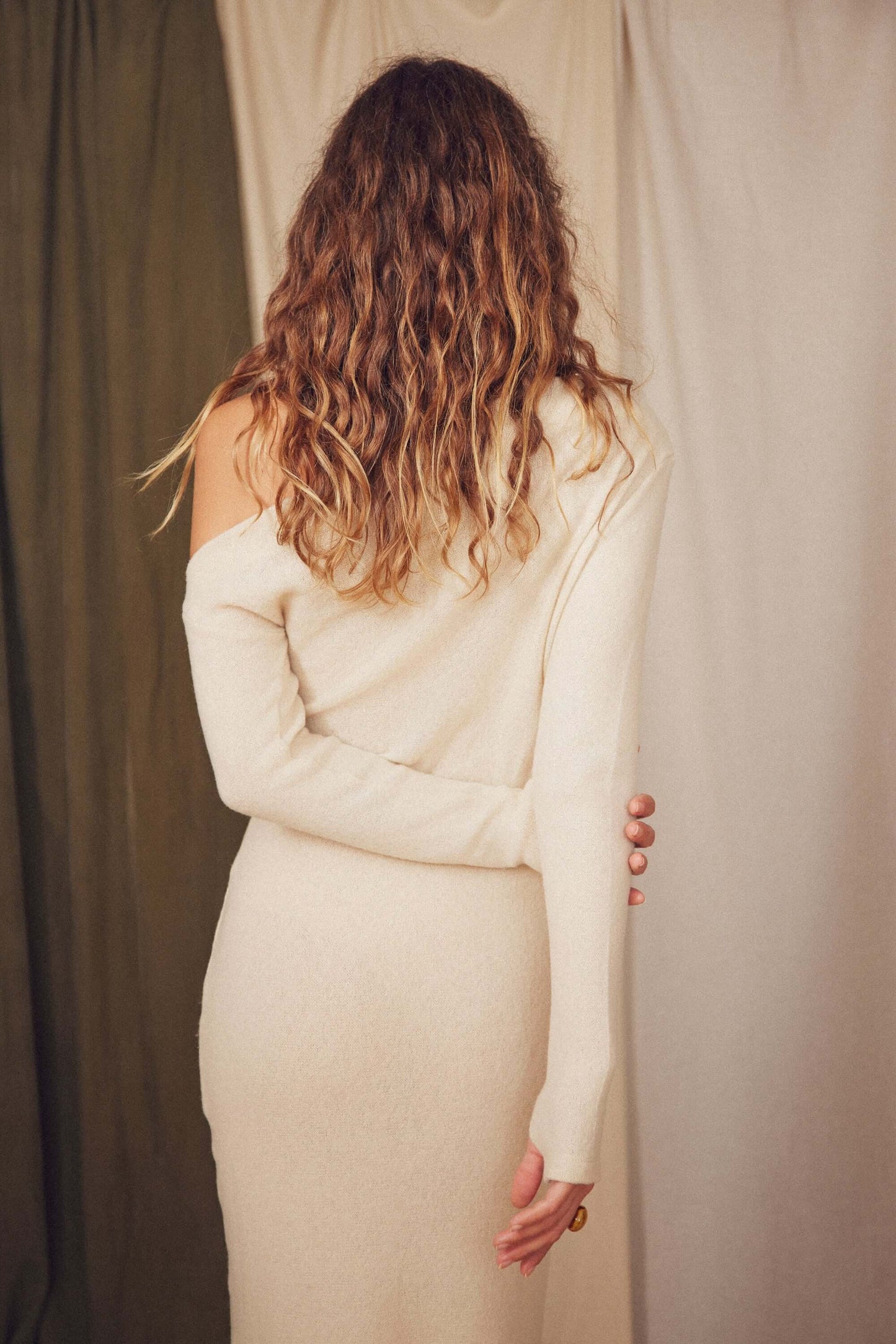Back view of a model wearing the Oat Fine Knit Drape Dress with a drape neckline and slim fit.