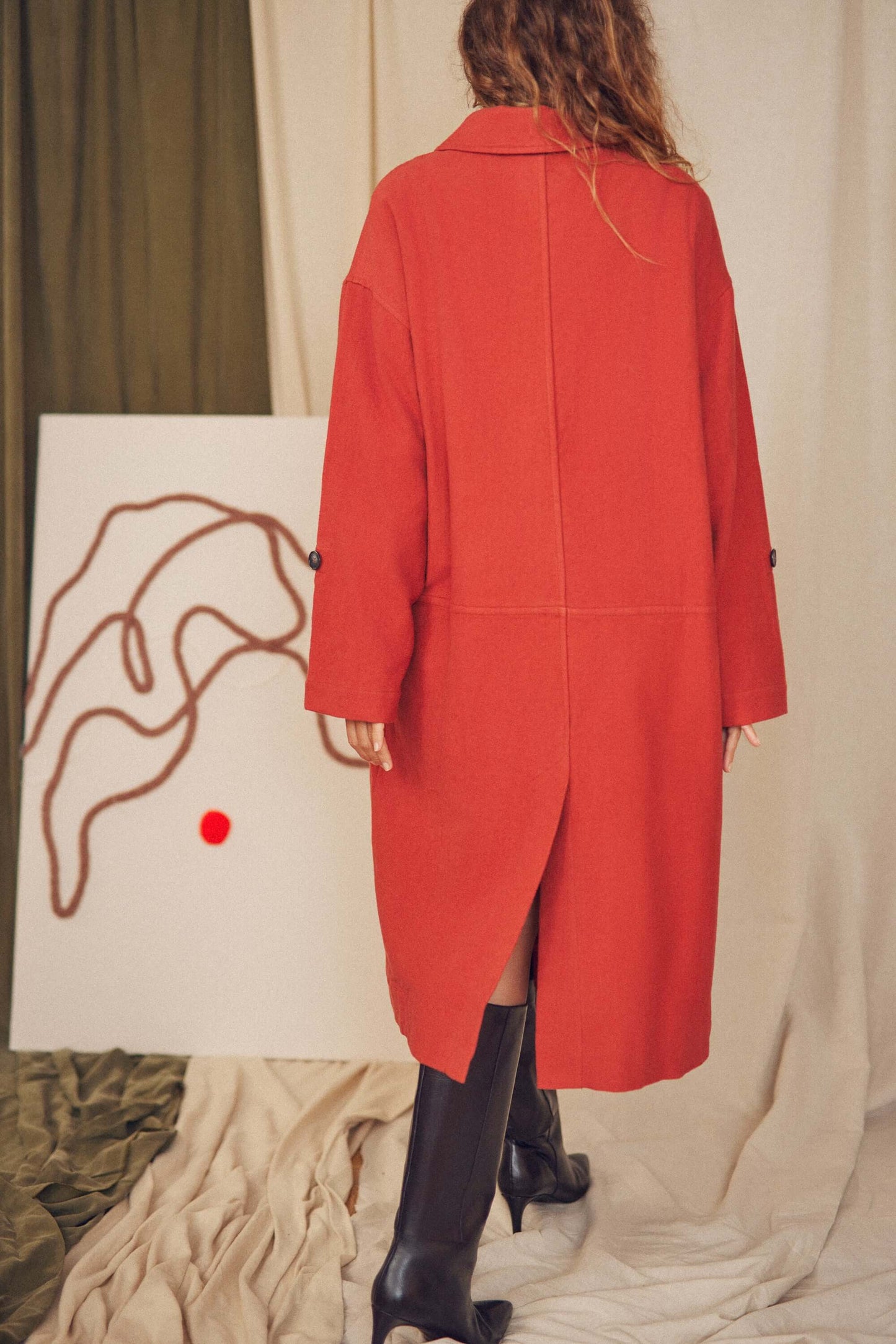 Woman wearing a rust wide coat.