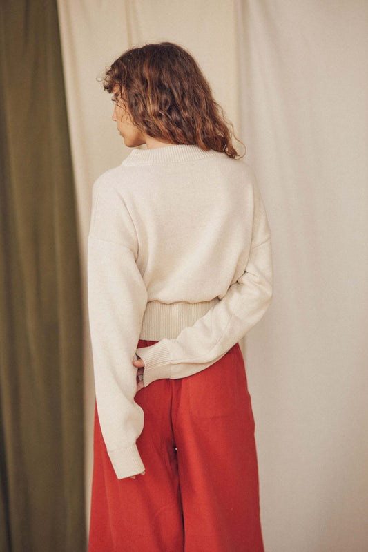 Back view of a model wearing the Jacquard Cotton Knit Sweater - ARCHIVE SALE with red pants.