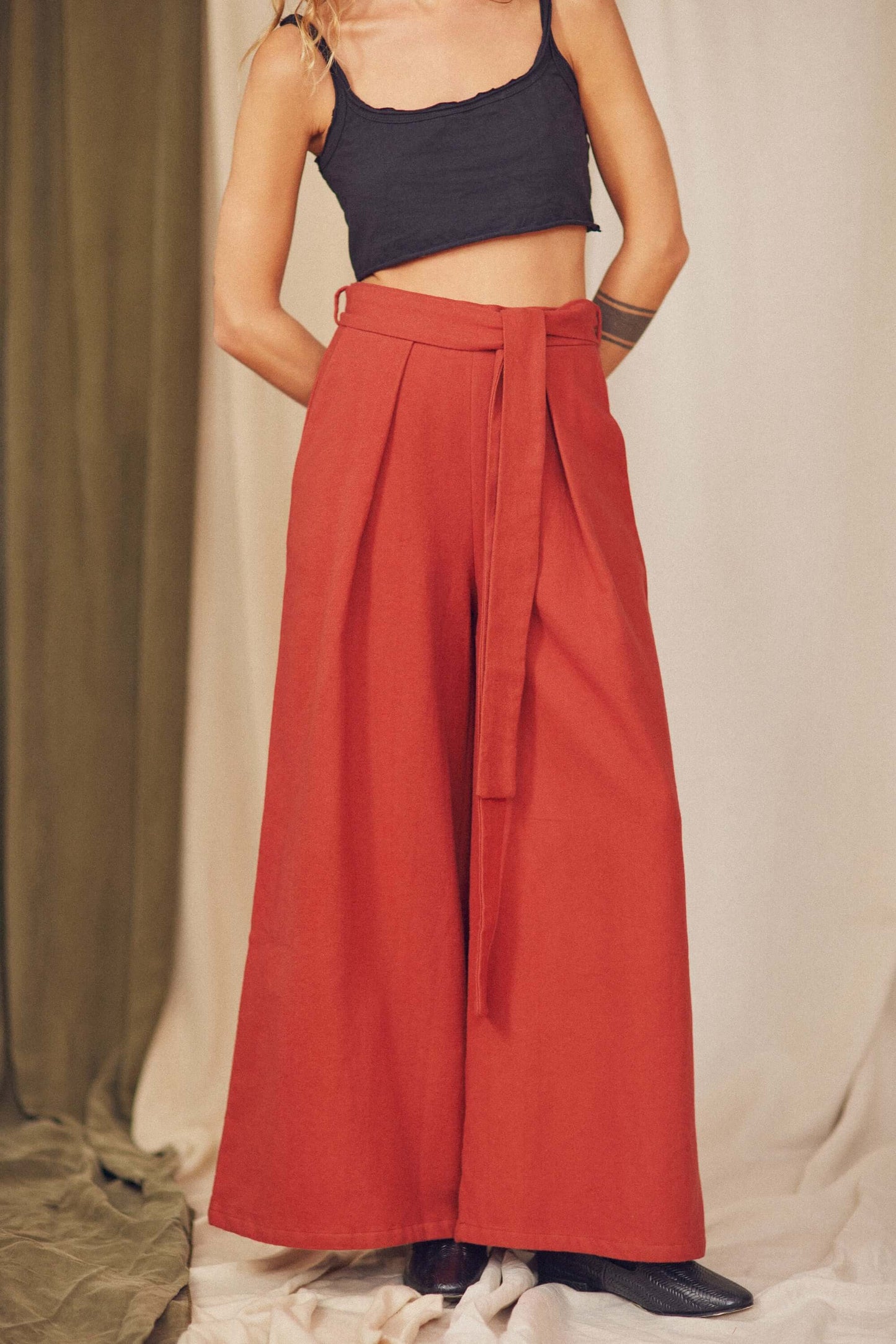 Woman styling rust organic cotton wide trousers with a black crop top.