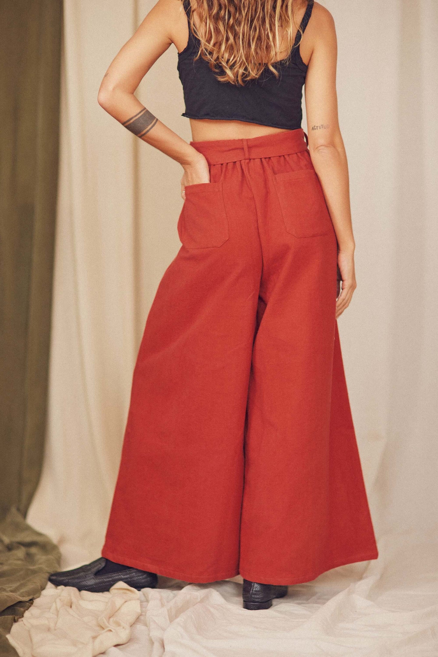 Woman styling rust organic cotton wide trousers with a black crop top.