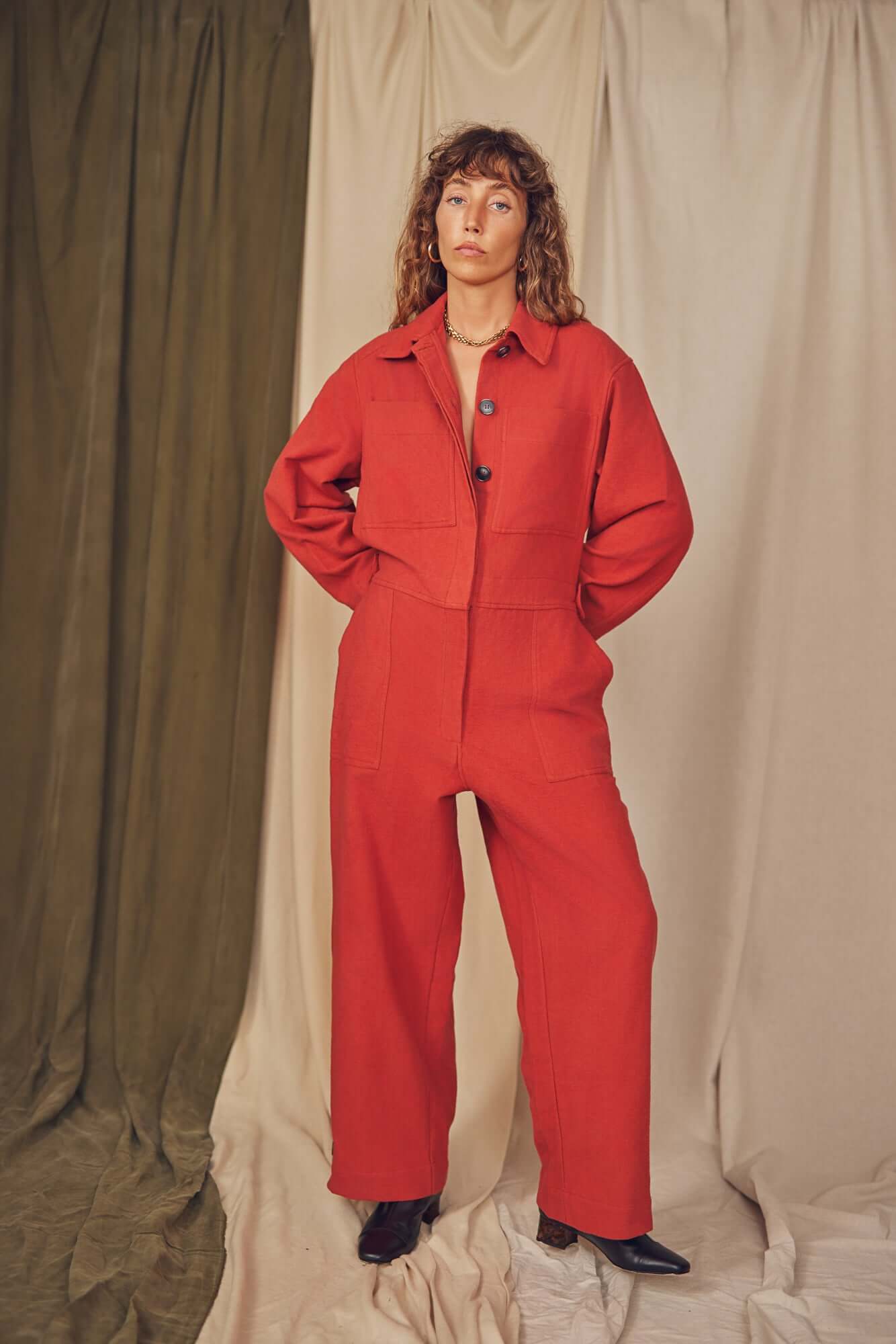 Woman wearing a rust colour boiler suit.