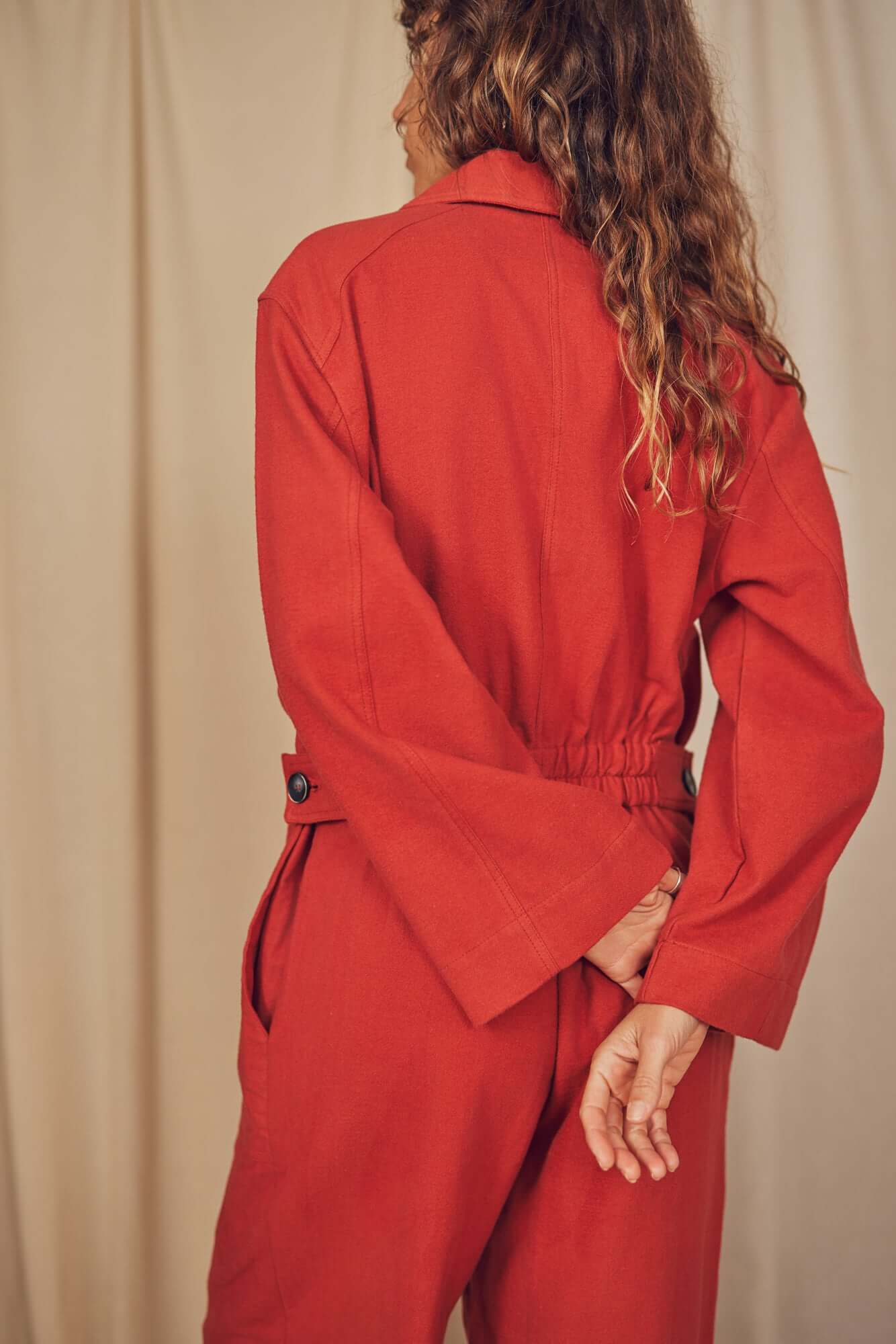 Woman wearing a rust colour boiler suit.
