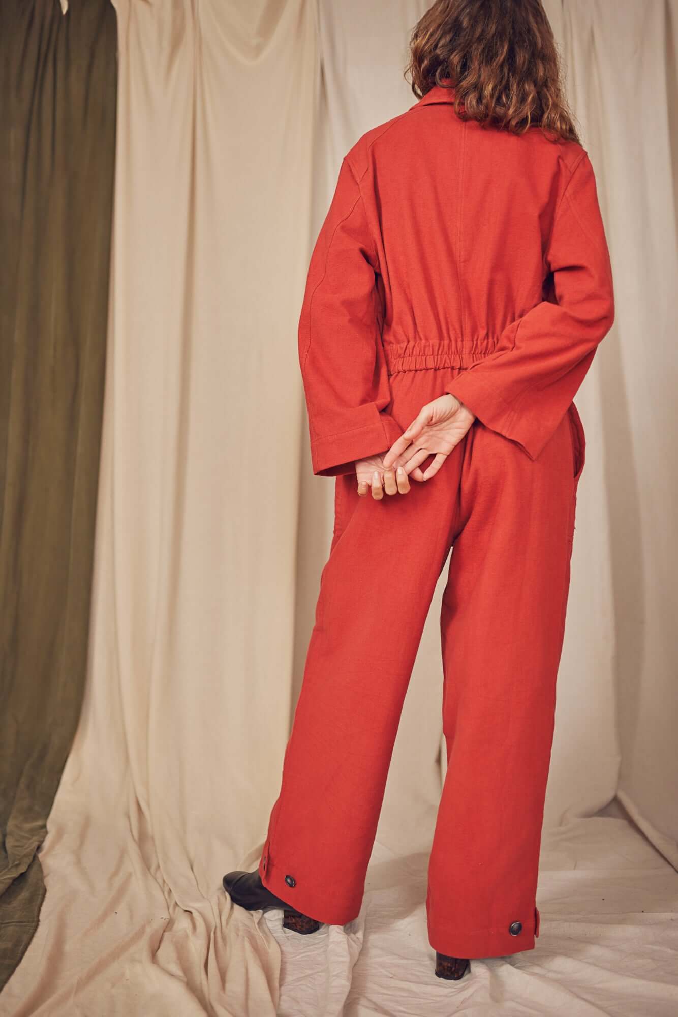 Woman wearing a rust colour boiler suit.