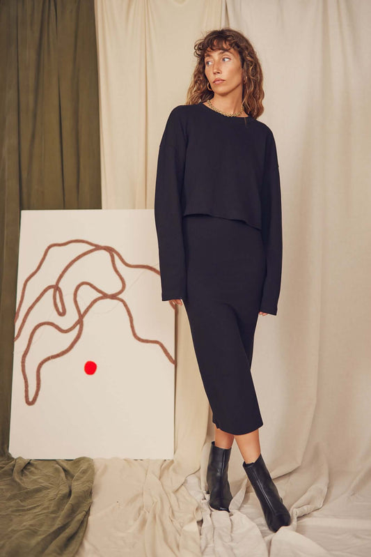 Model wearing a black organic cotton long sleeve crop top and matching skirt, showcasing a minimalist autumn look.