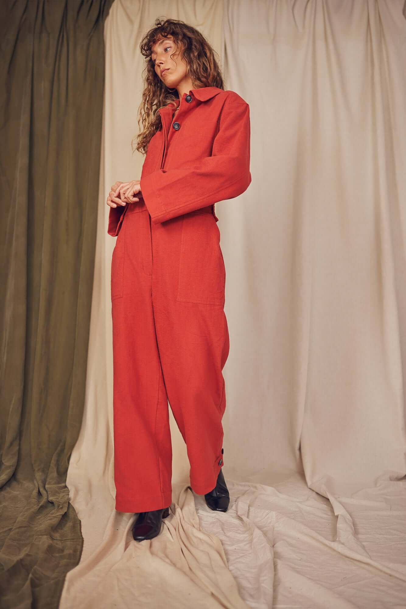 Woman wearing a rust colour boiler suit.