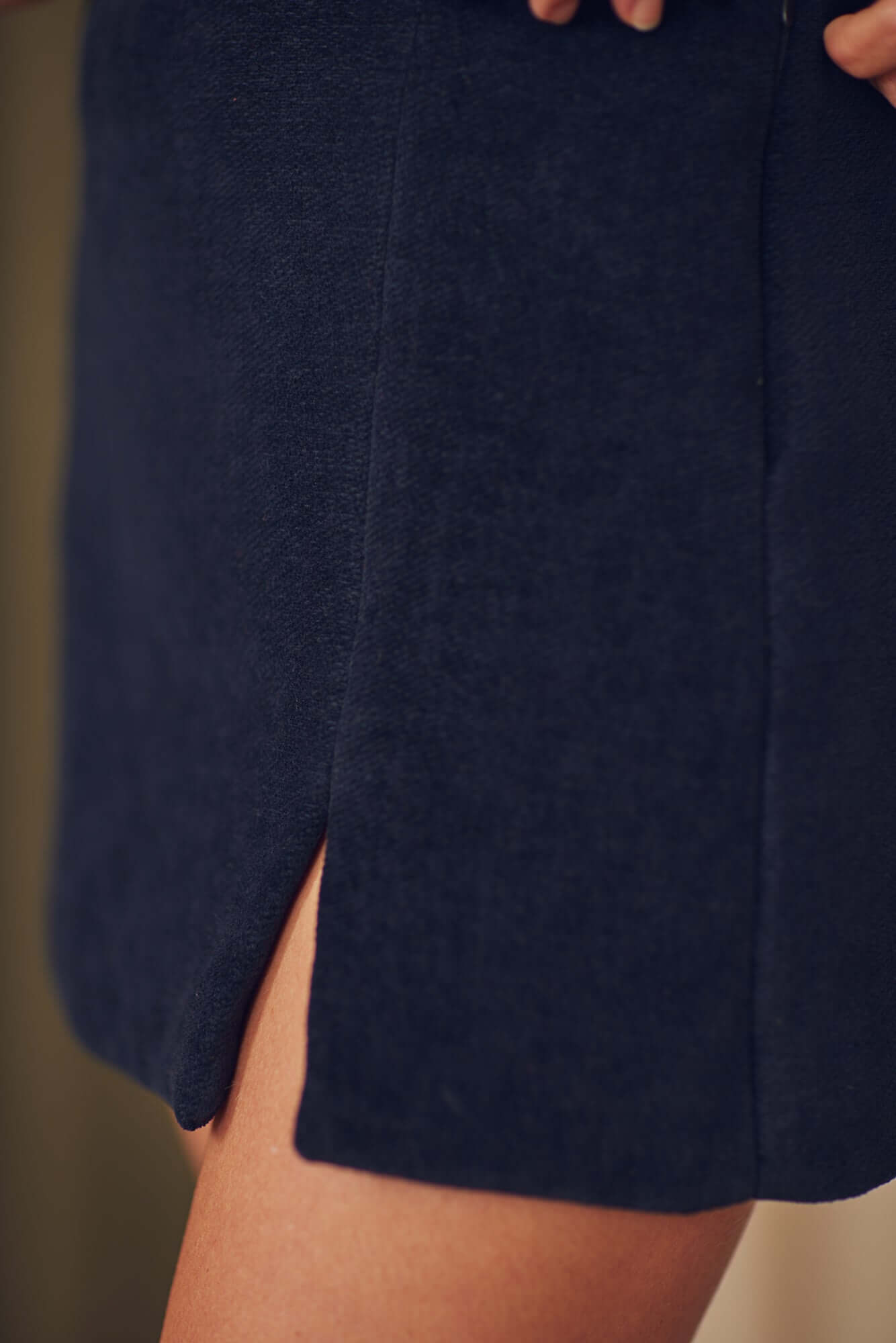 Close-up of black organic cotton mini skirt featuring a chic thigh split, perfect for autumn/winter styling.