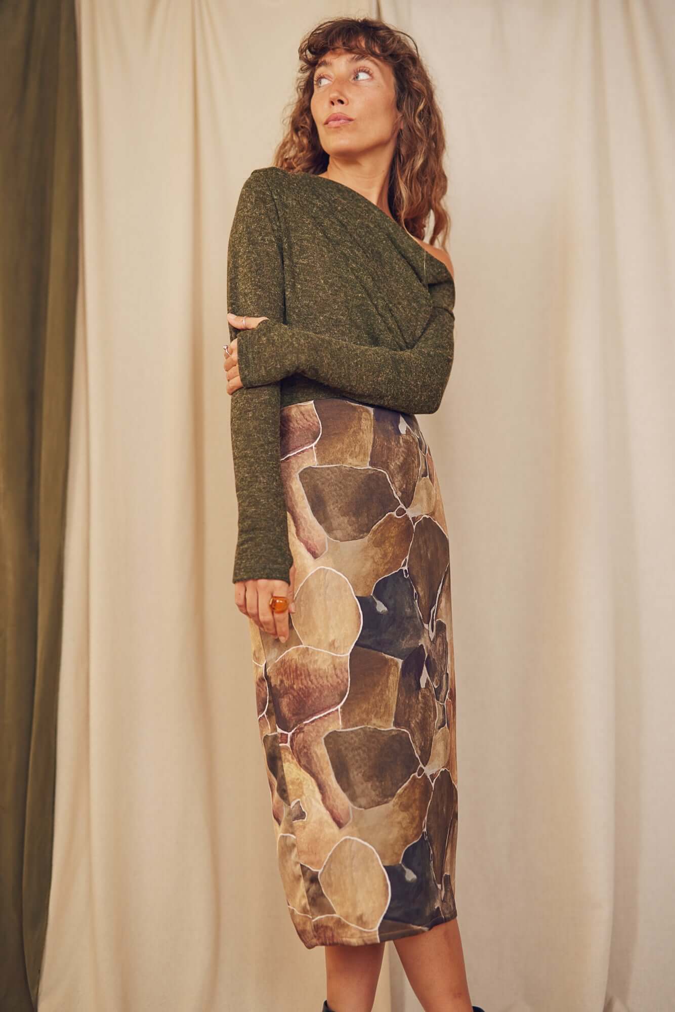 Model wearing a khaki recycled jersey drape bodysuit with a patterned skirt, showcasing sustainable autumn fashion.