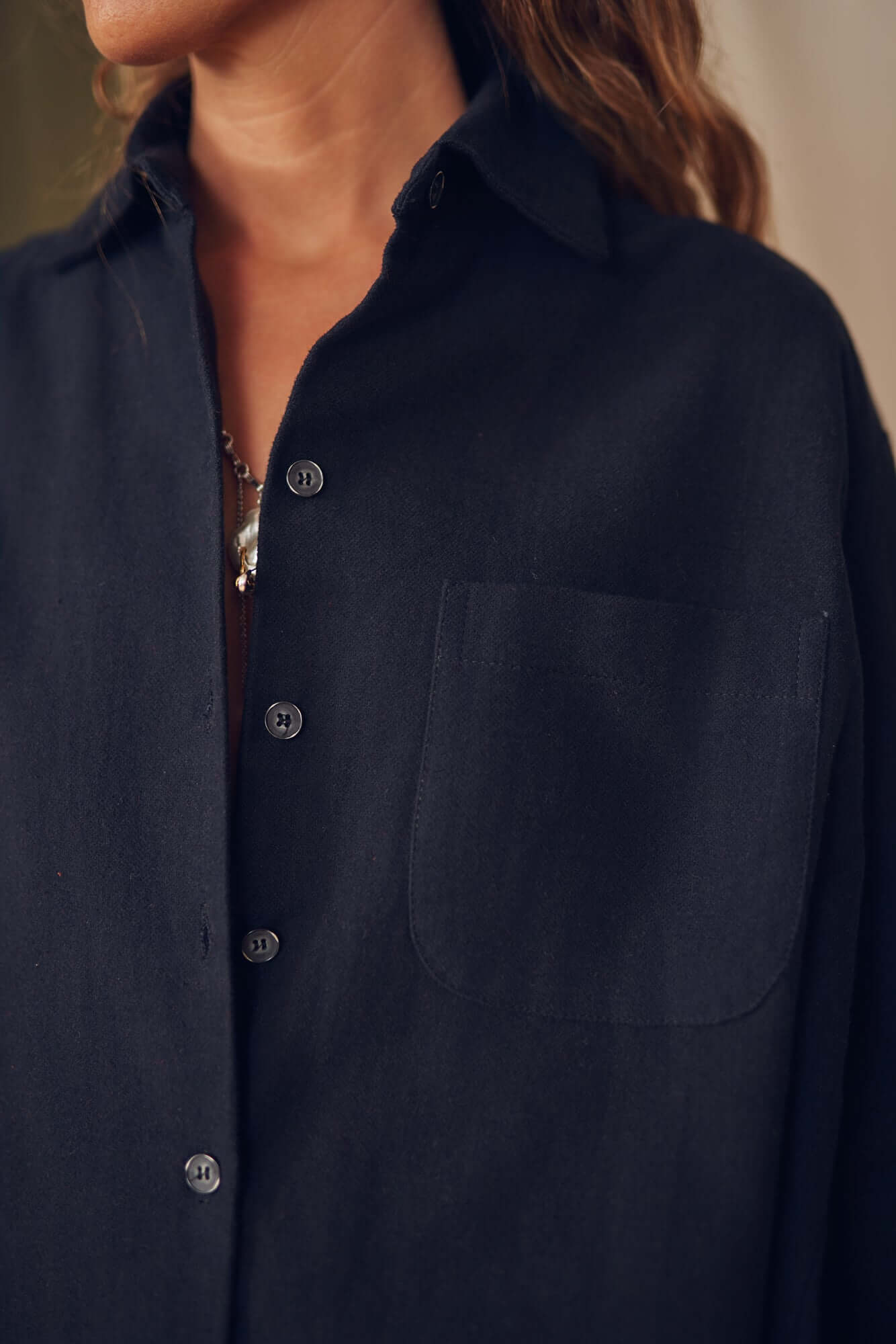 Close-up of black organic cotton wide overshirt featuring buttons and pocket detail, perfect for layering.