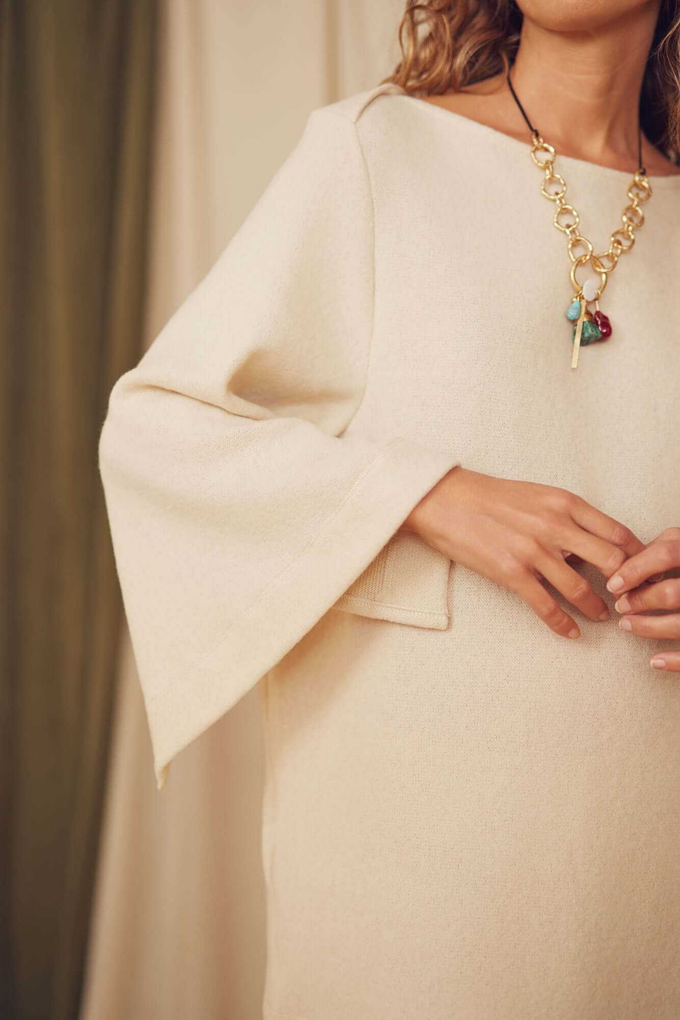 Model wearing an Oat Fine Knit Mini Dress with flared sleeves and a statement necklace.