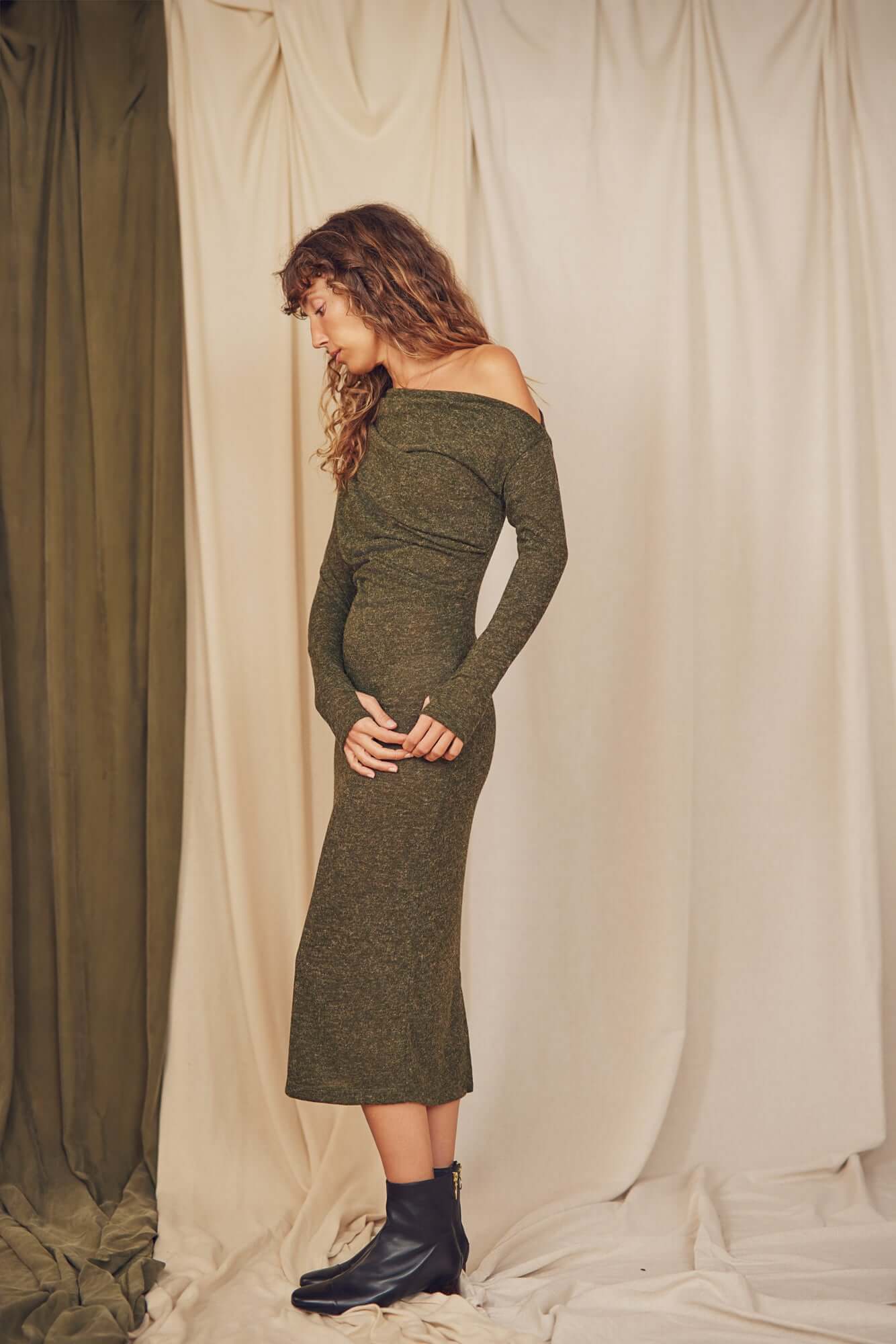 Model wearing a khaki recycled jersey drape midi dress with thumb holes on a neutral backdrop.