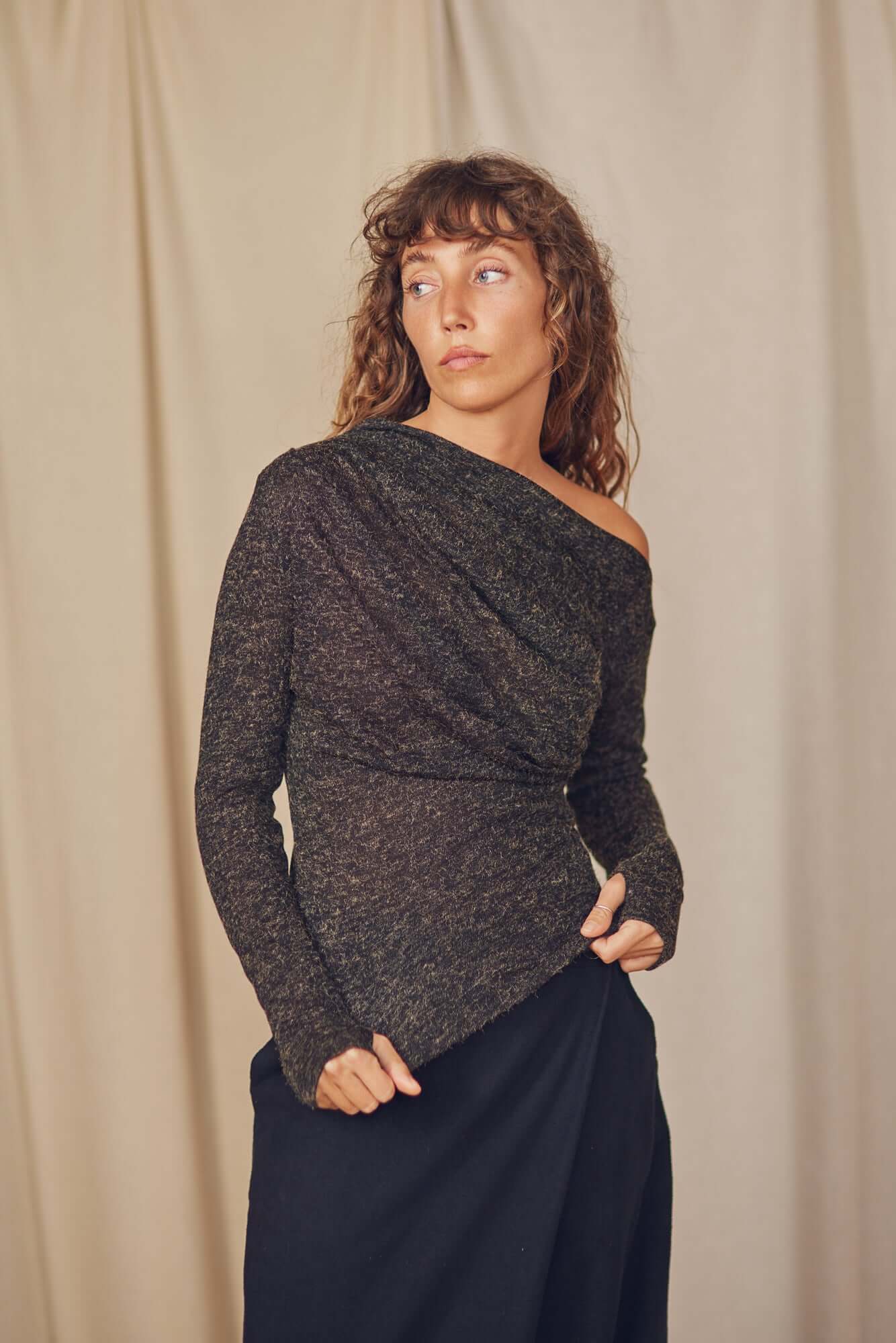 Model wearing a black recycled jersey drape top with a stylish neckline and thumb holes, perfect for autumn layering.