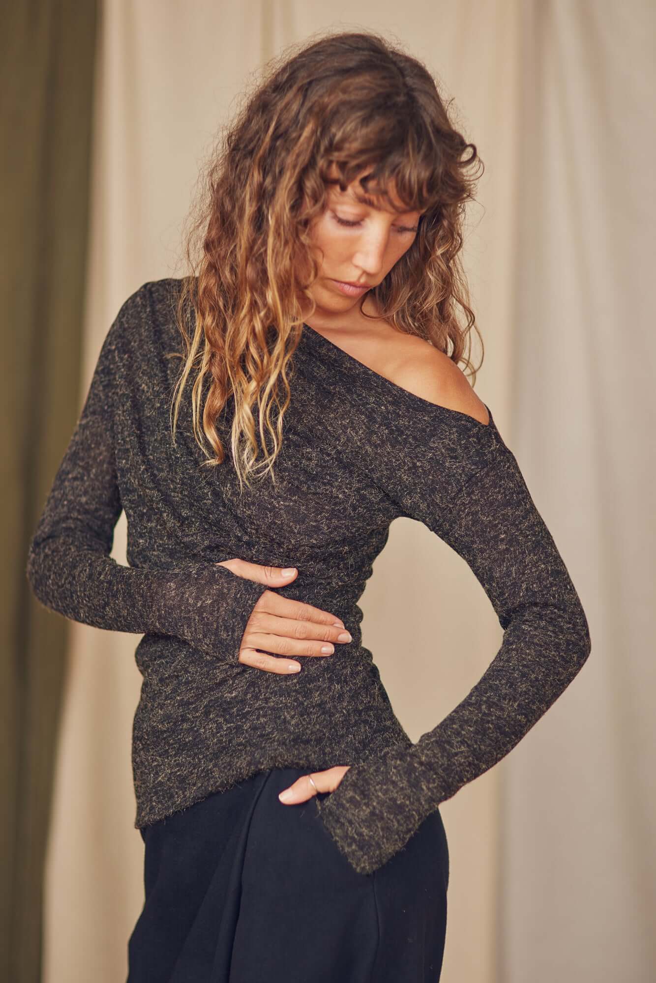 Model wearing a black recycled jersey drape top with chic draped neckline and thumb holes, styled for autumn layering.