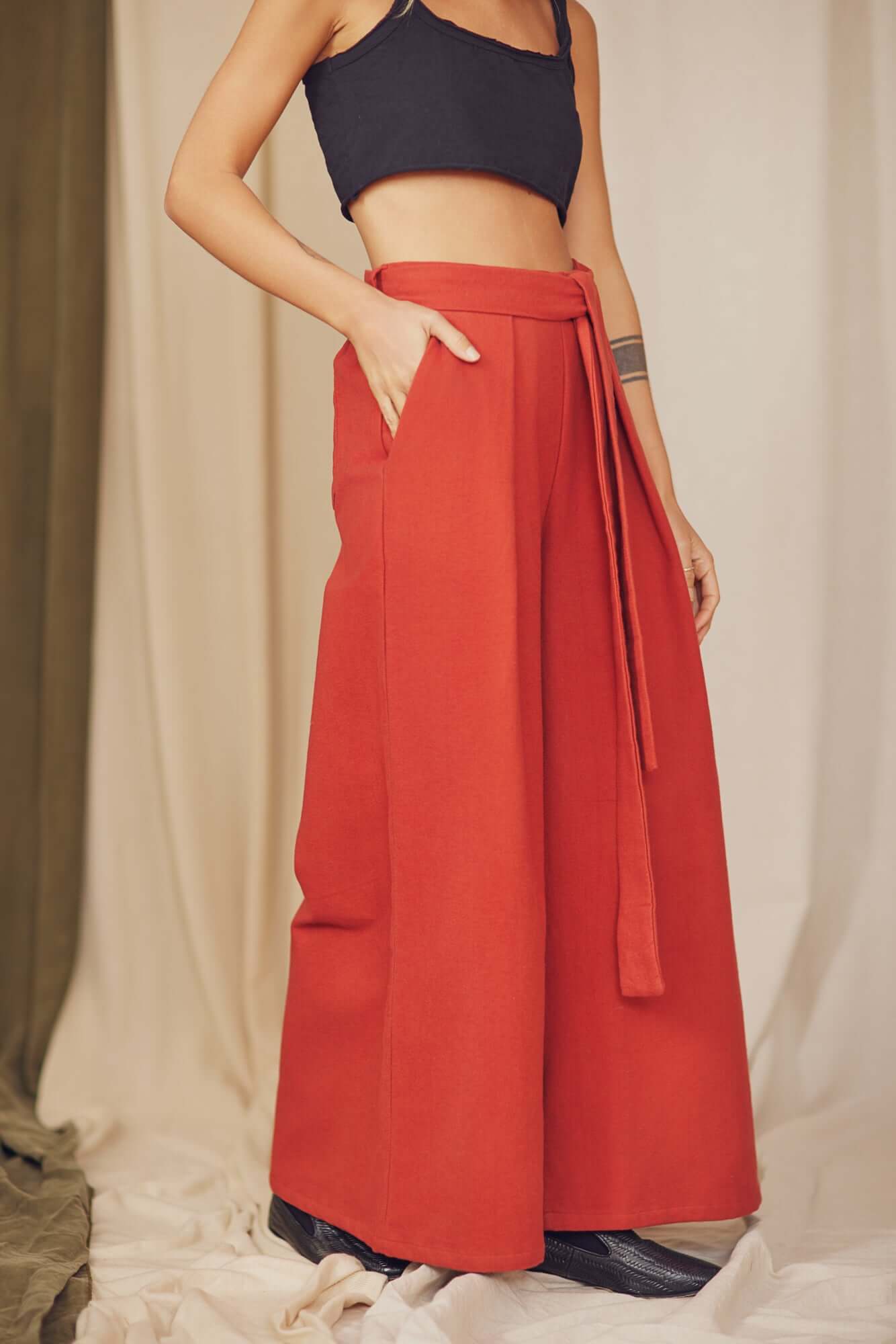 Woman styling rust organic cotton wide trousers with a black crop top.