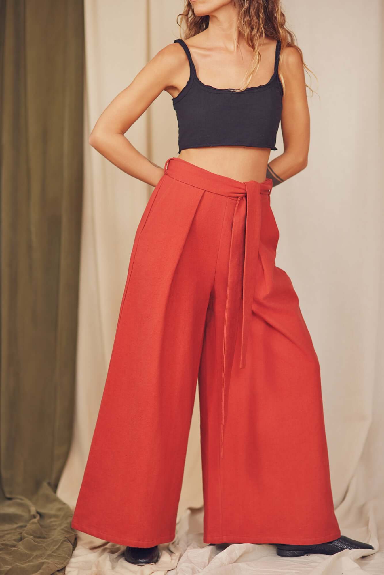 Woman styling rust organic cotton wide trousers with a black crop top.