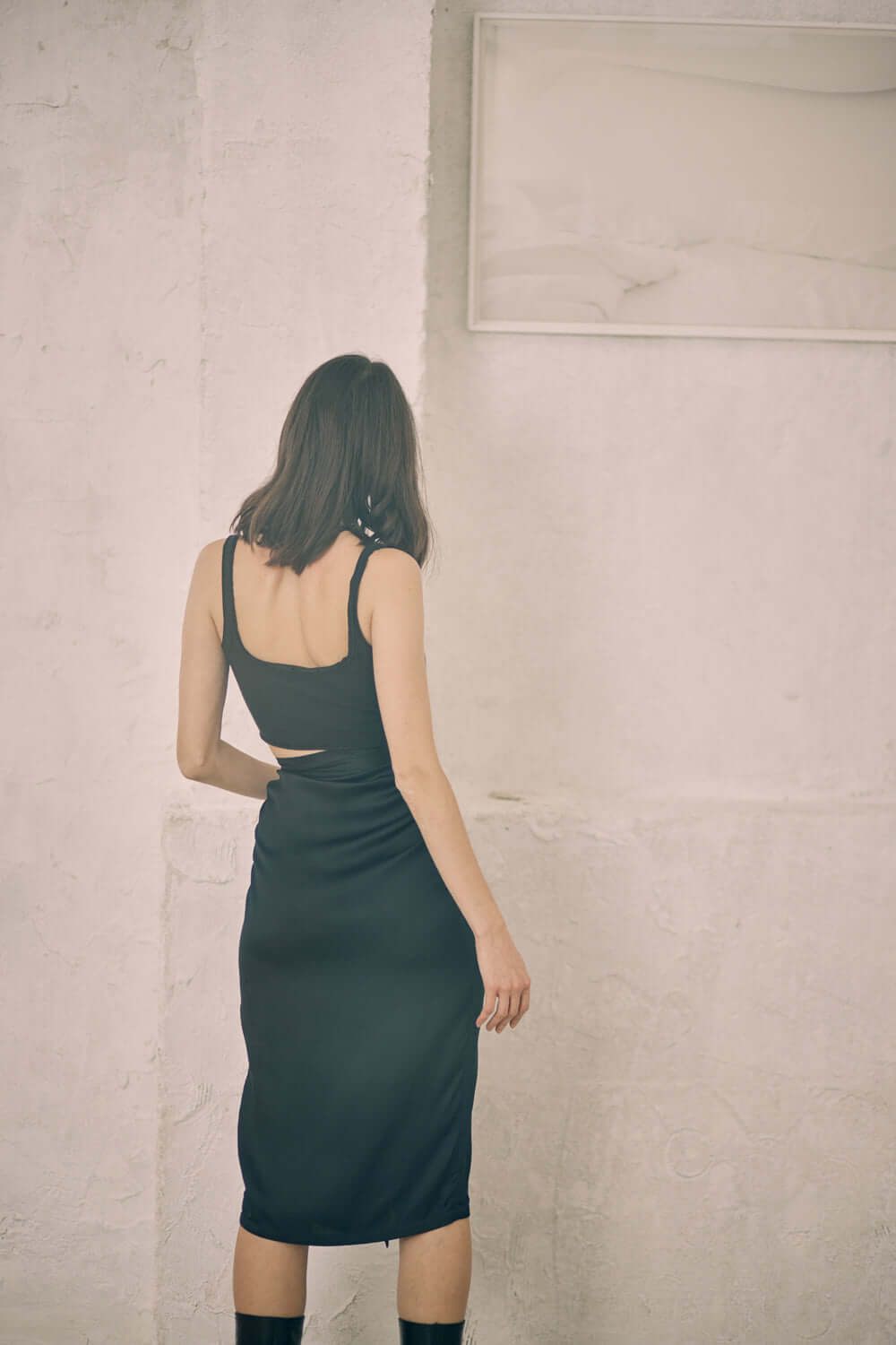 Model in a black wrap midi skirt showcasing self-tie closure and woven Ecovero viscose material.